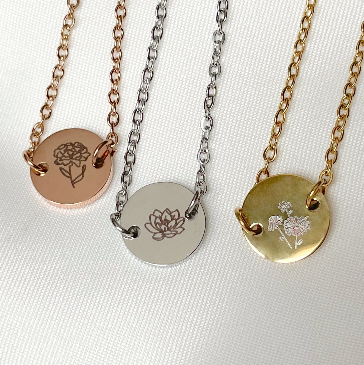 Close up front view of three bracelets with circular charms featuring floral designs on a white background
