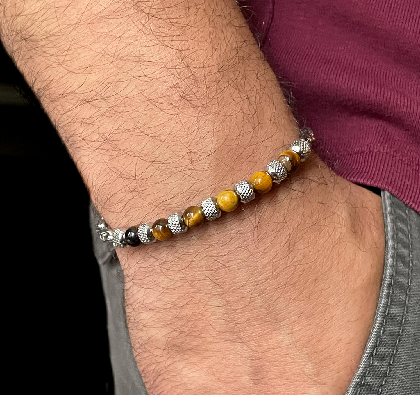 Close-up of a wrist wearing a  brown beaded silver chain bracelet with tiger eye stones and textured steel beads