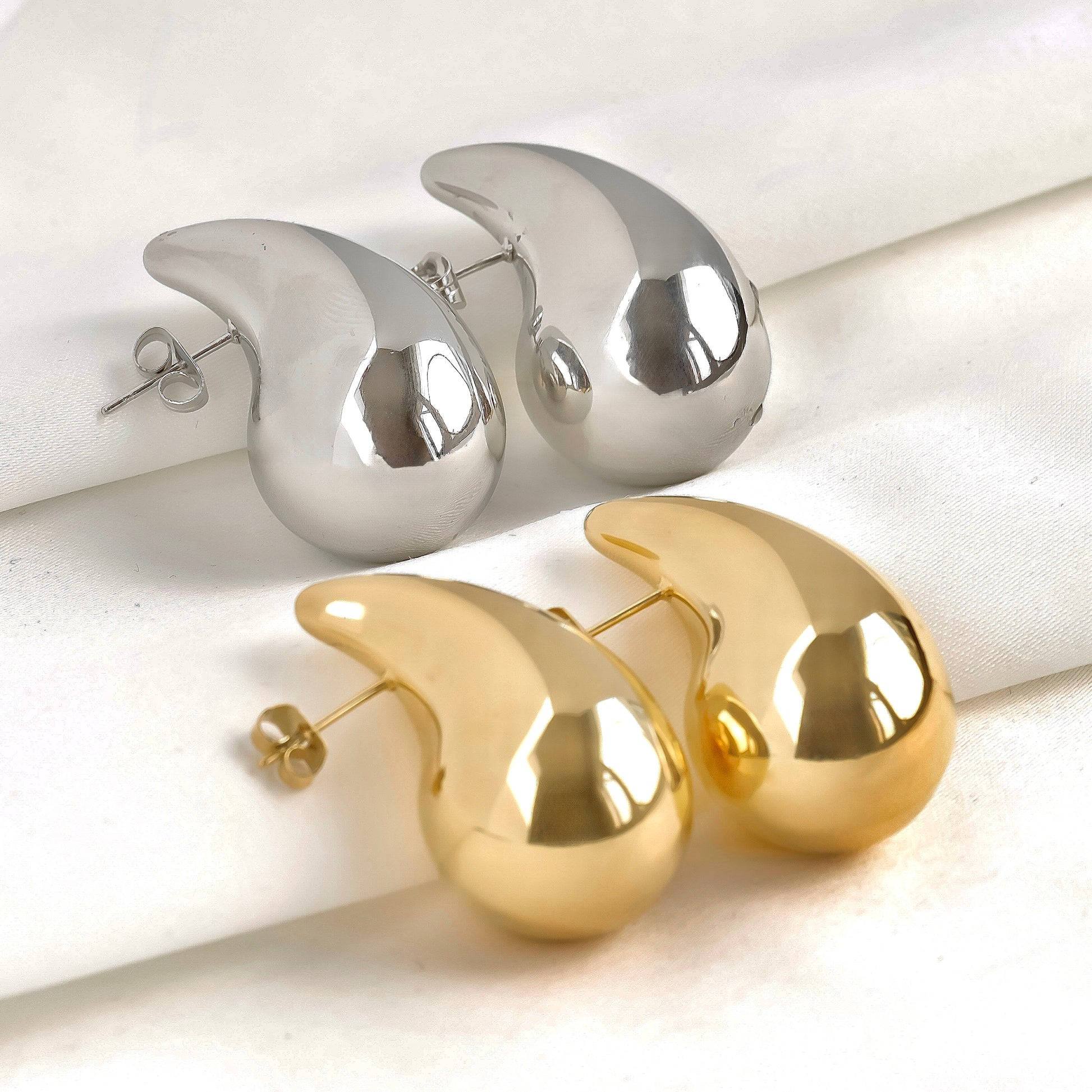 Pair of gold and silver waterdrop earrings on a light background