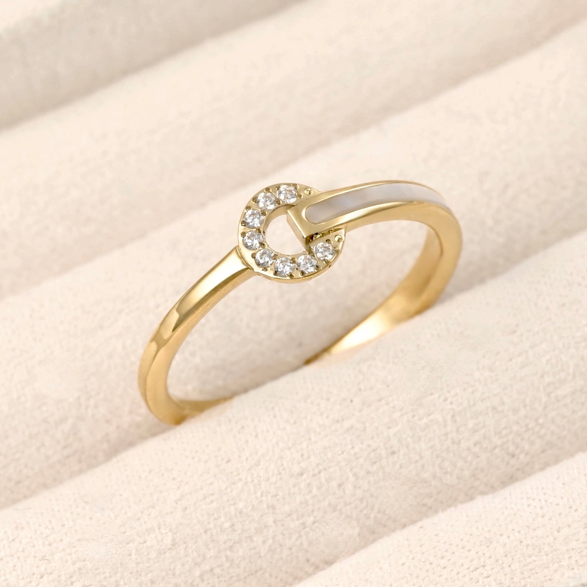 Gold circle ring adorned with cz stones and shell inlay on one side of the band, displayed in a beige jewelry box.