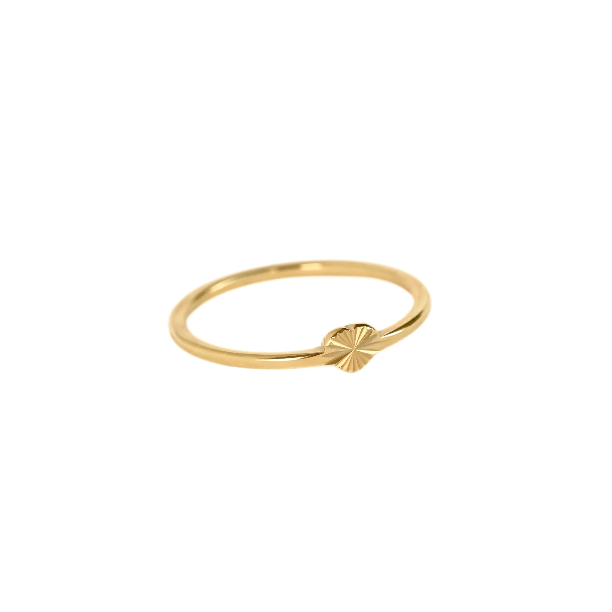 A dainty gold heart ring with a small textured starburst detail on the front, set against a plain white background.