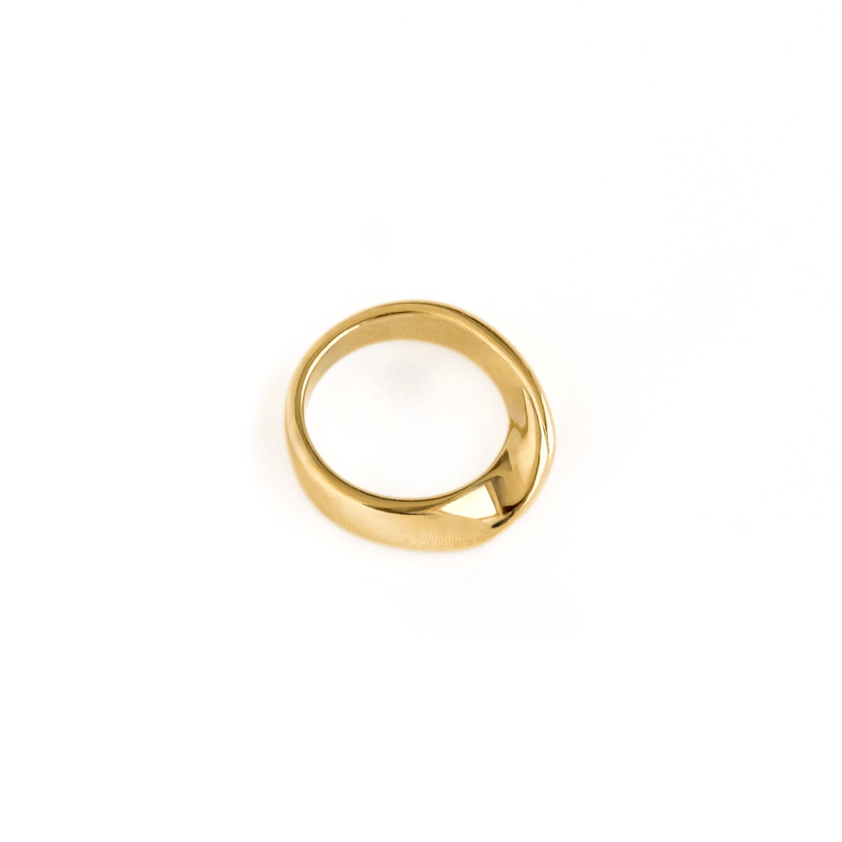 A polished gold ring with a unique twisted band design, photographed on a seamless white background.