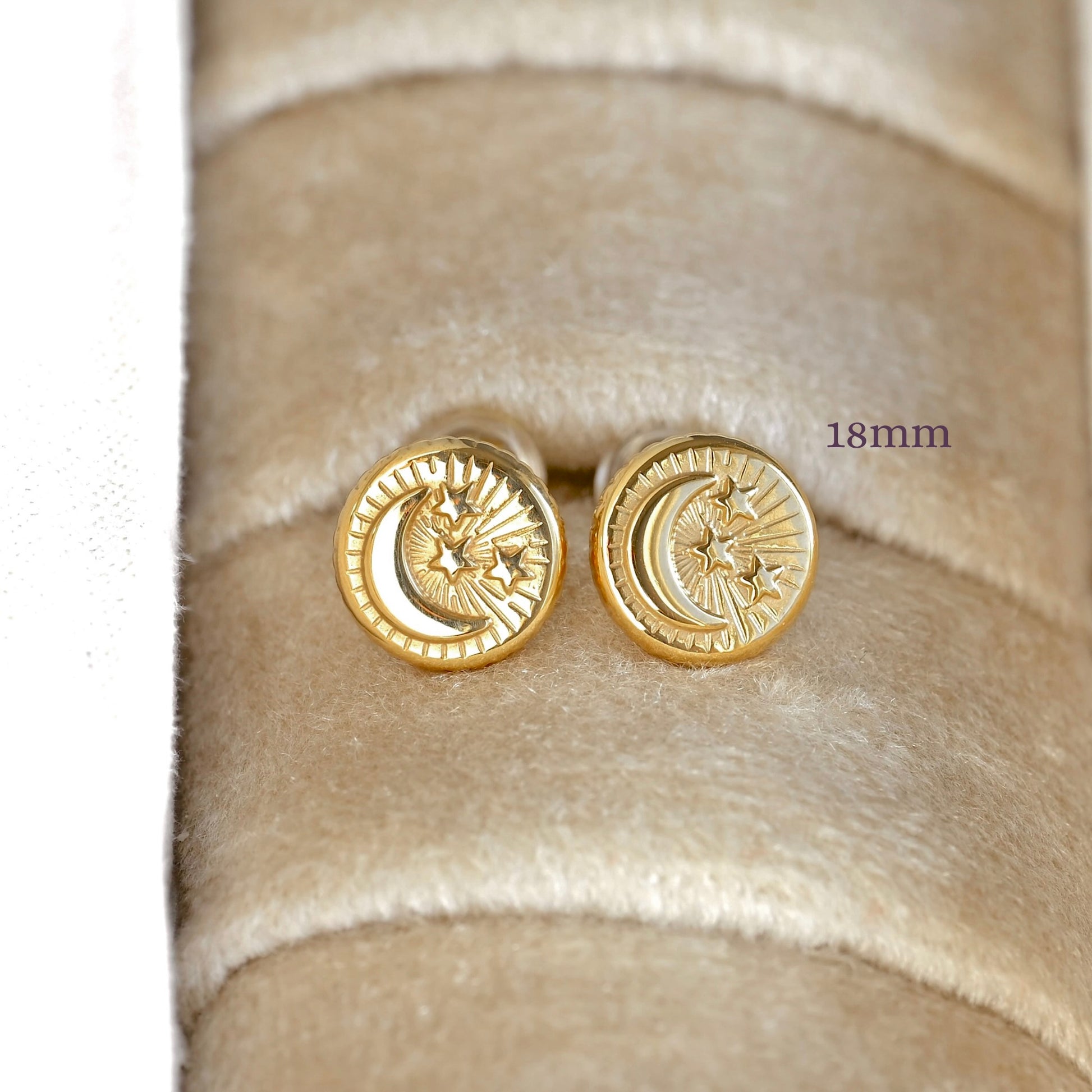 A pair of round gold-tone stud earrings with a crescent moon and star design, displayed on a beige velvet jewelry ring. The text '18mm' indicates the size of the studs.