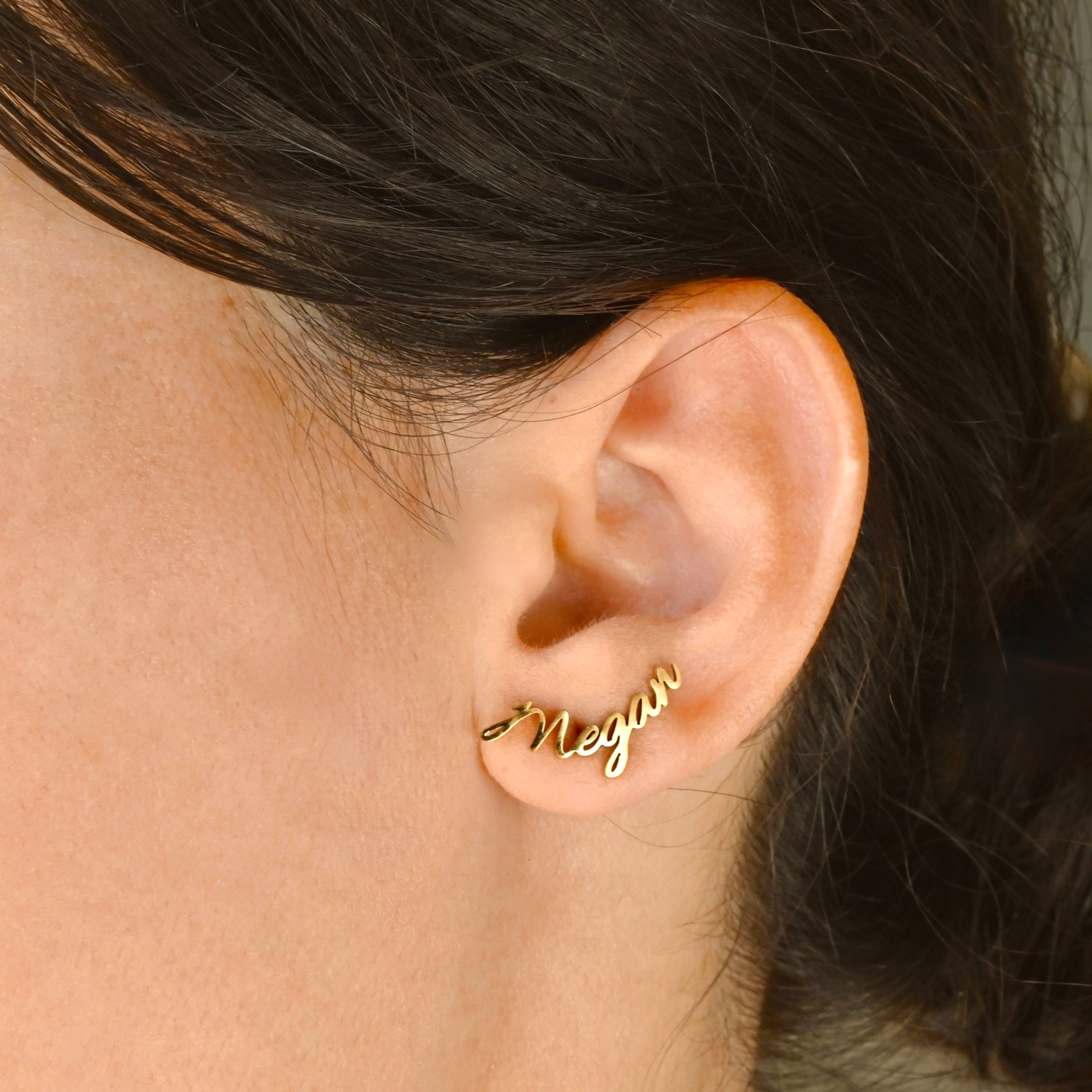 Gold name earrings worn by a person
