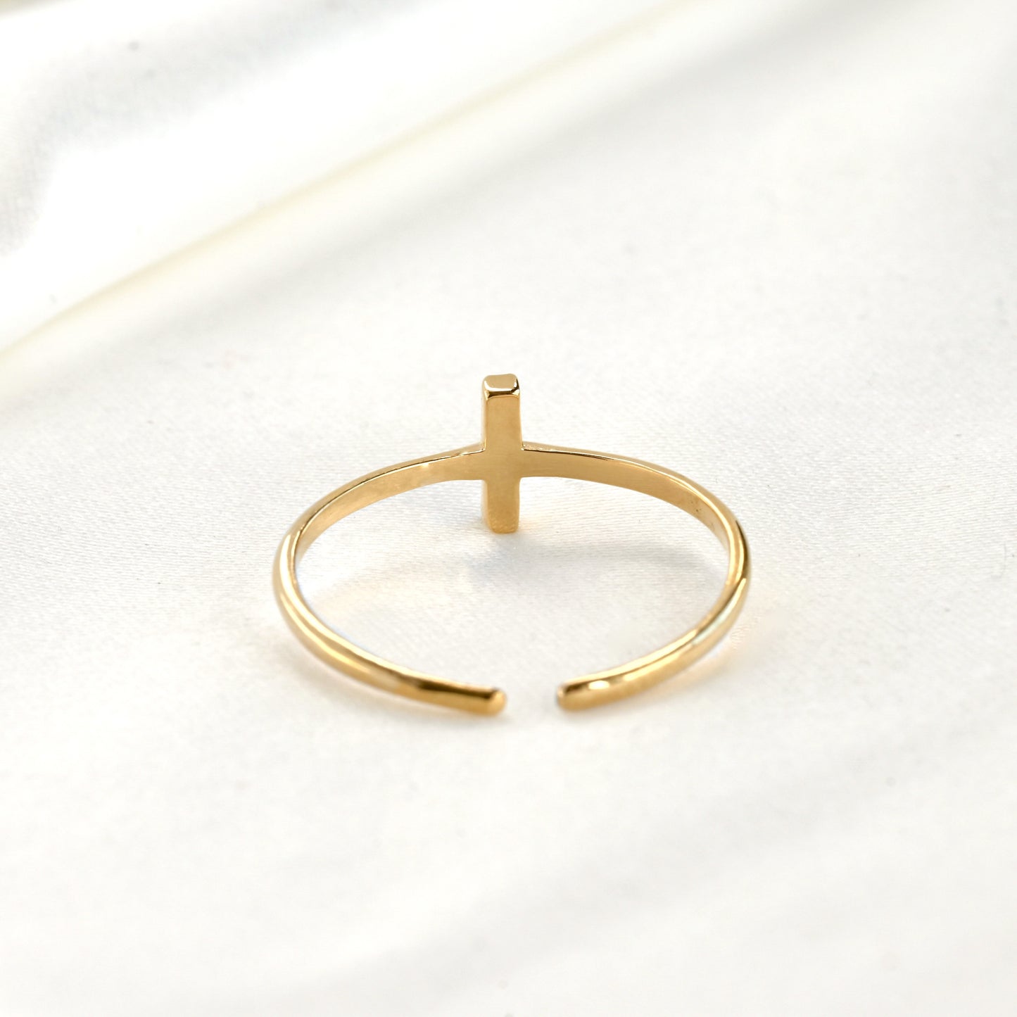 Back side view of gold ring with a vertical bar and adjustable open design on a white background