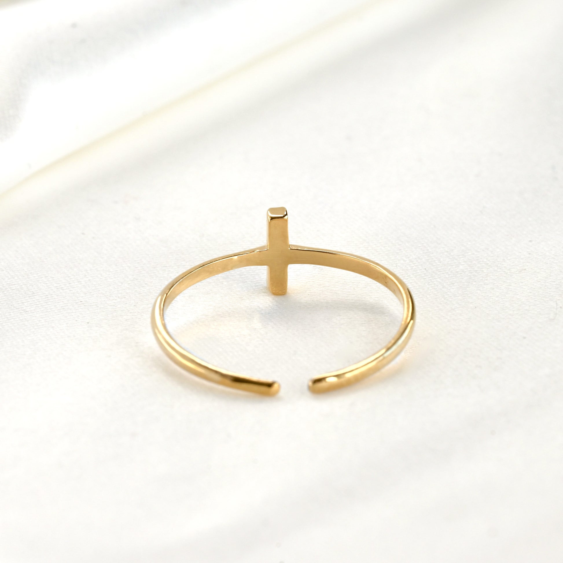 Back side view of gold ring with a vertical bar and adjustable open design on a white background
