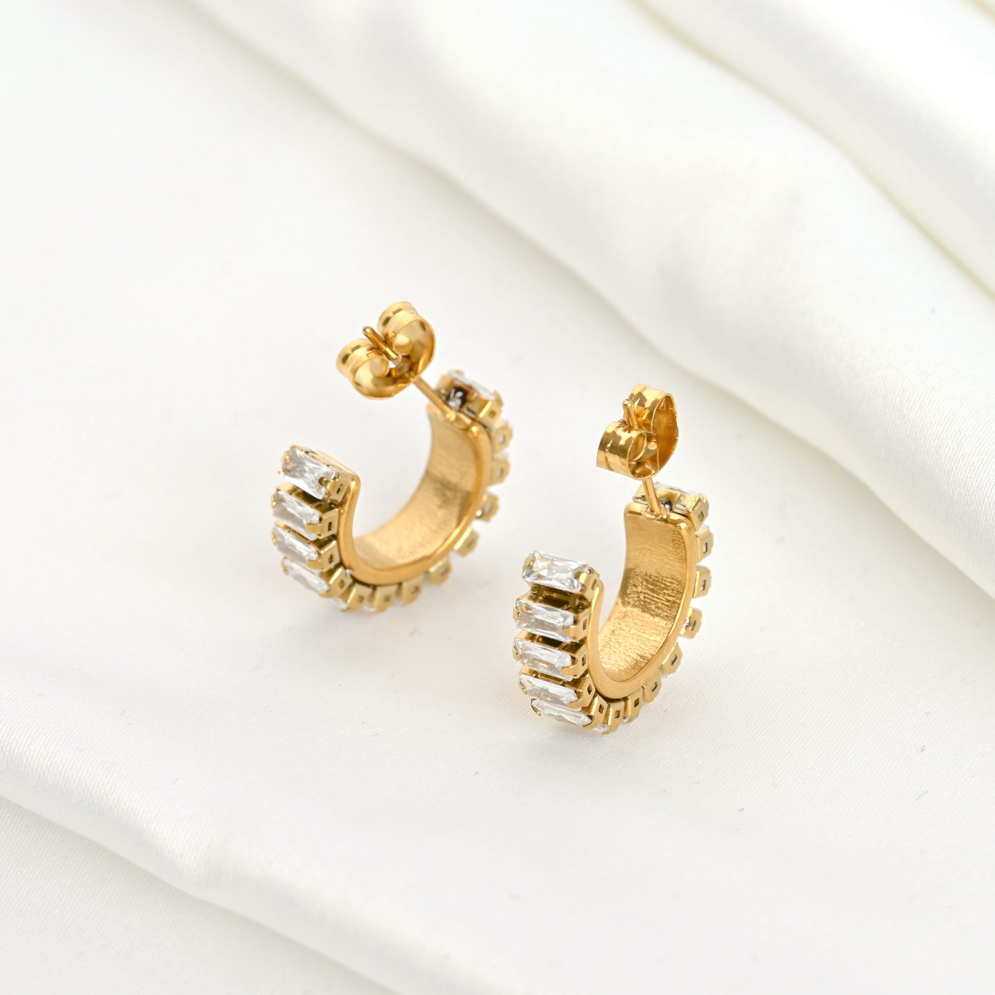 Close-up view of the inside of gold diamond hoop earrings on a white surface