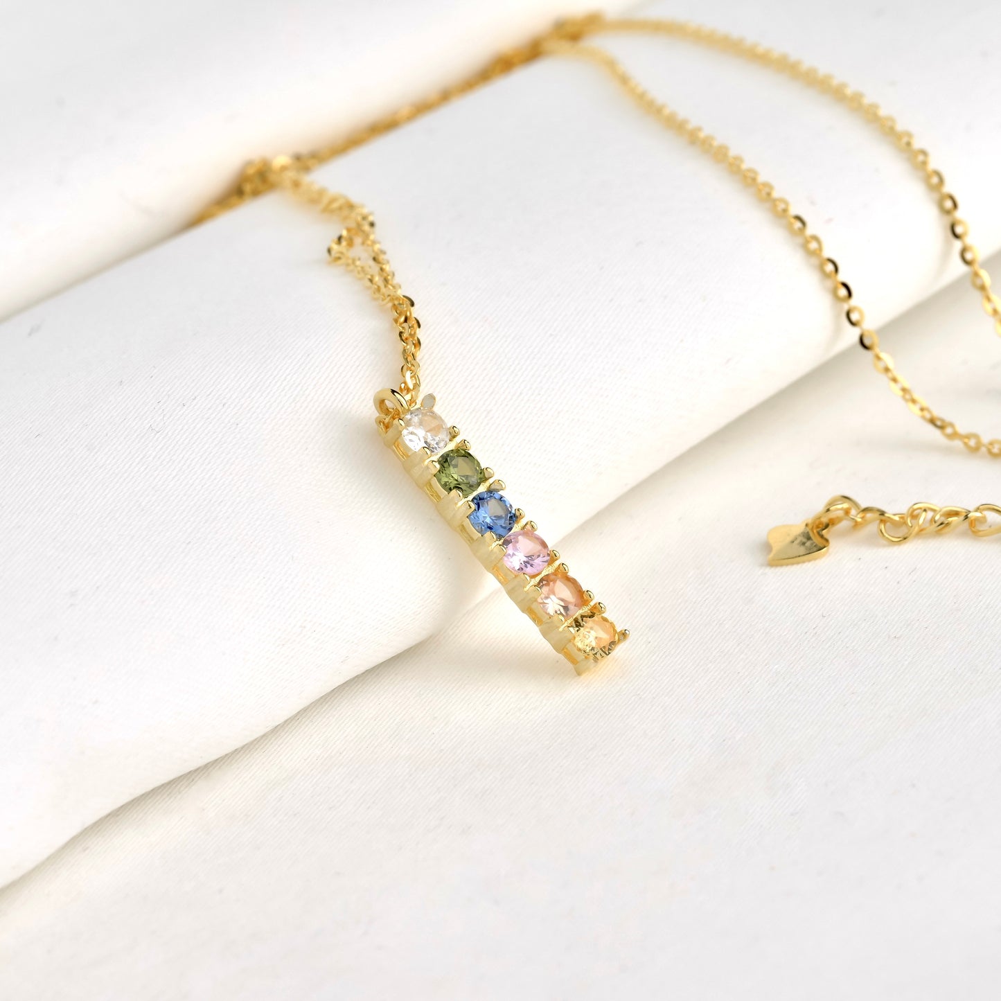 Gold bar necklace with birthstones on a white surface