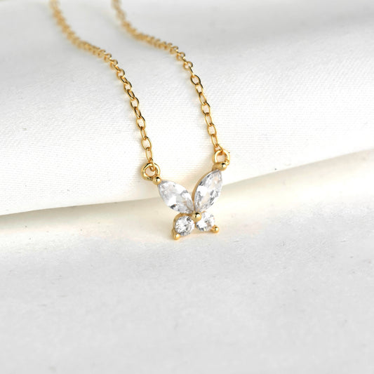 Gold butterfly necklace with clear gemstones on a white background
