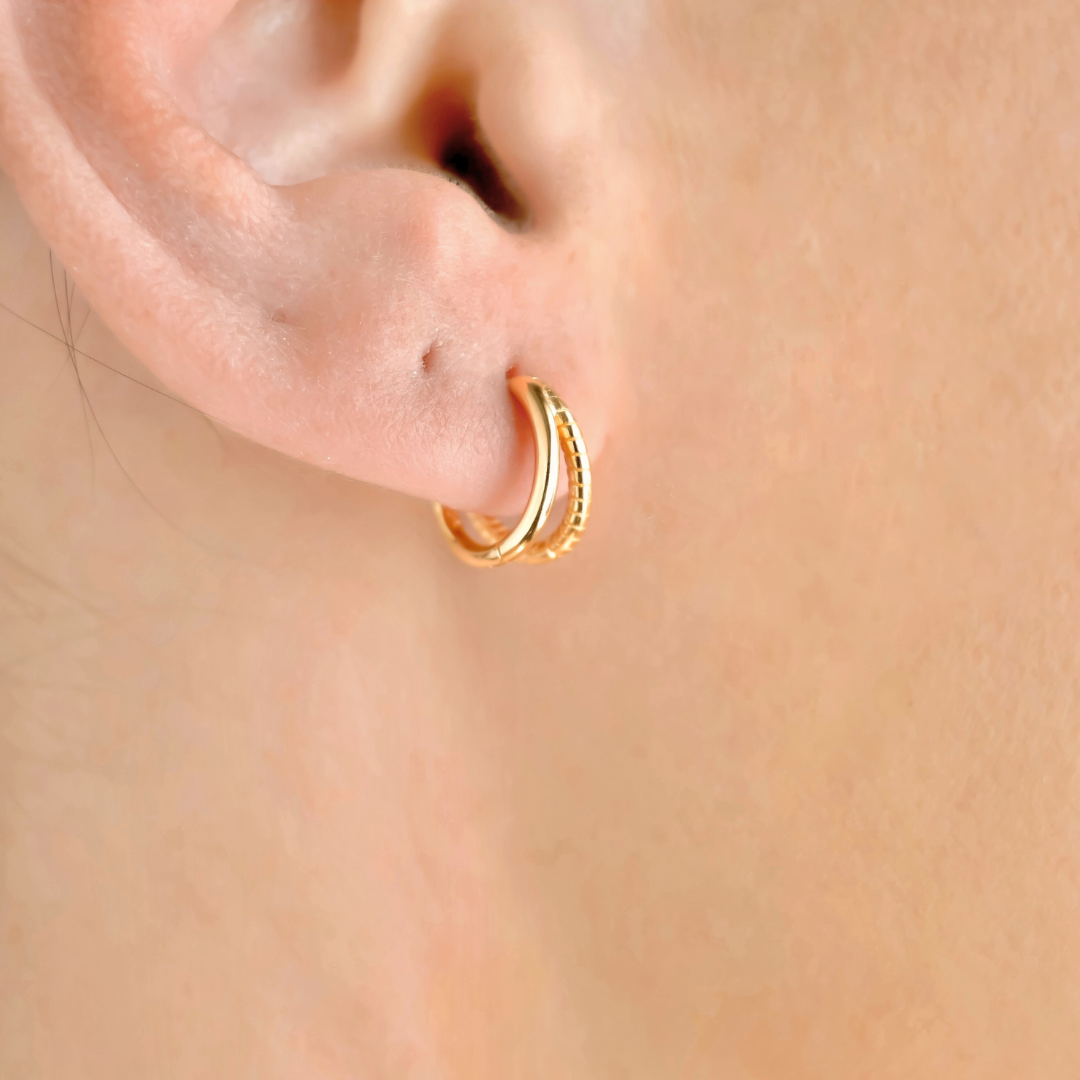 Gold split huggies worn on a person's ear