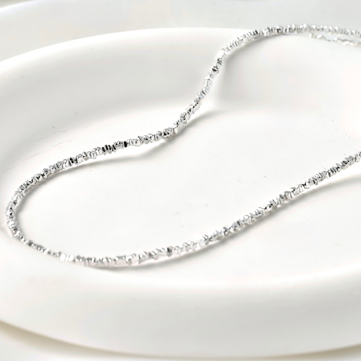 Silver beaded necklace on a white background