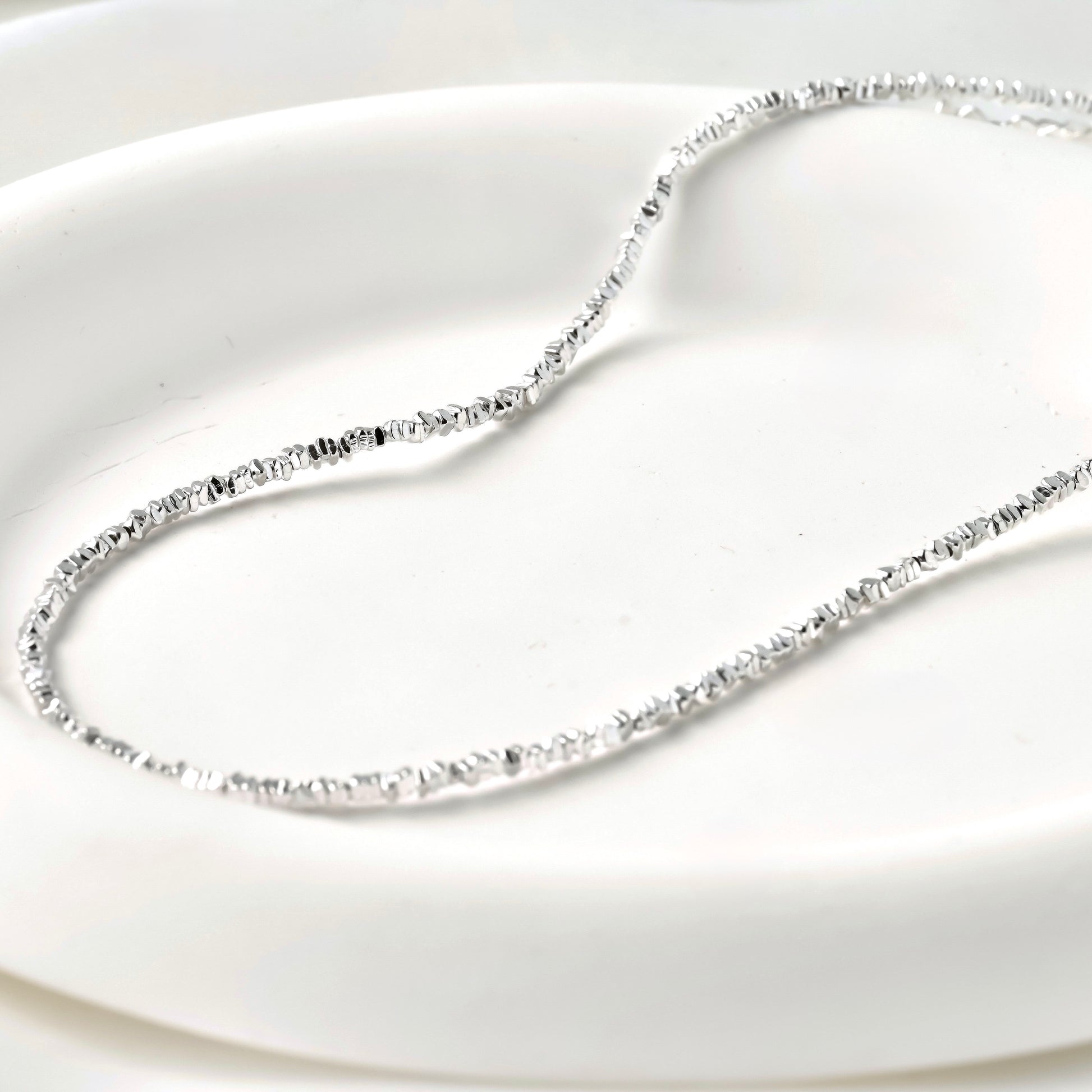 Silver beaded necklace on a white background