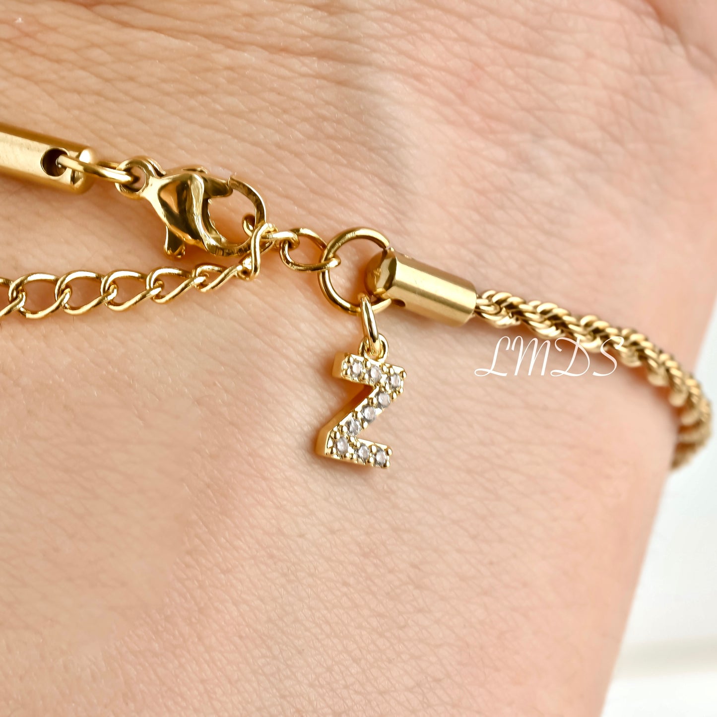 Gold rope bracelet with a CZ initial 'Z' charm on a wrist.