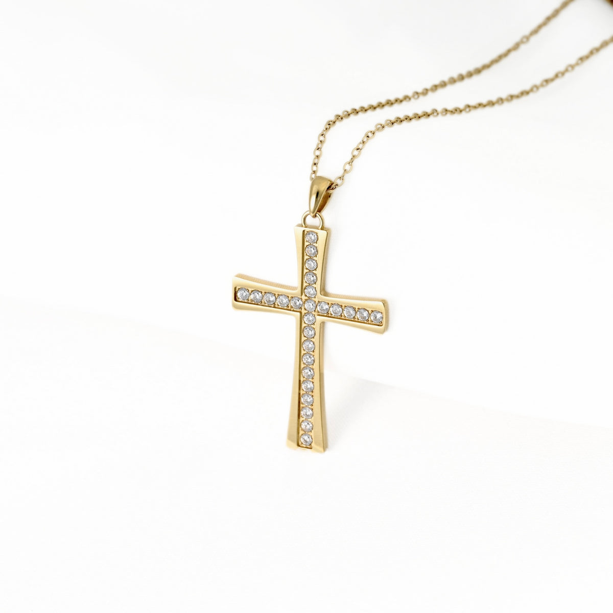 A gold cross pendant necklace adorned with small clear stones along its edges, suspended from a delicate gold chain against a clean white background.