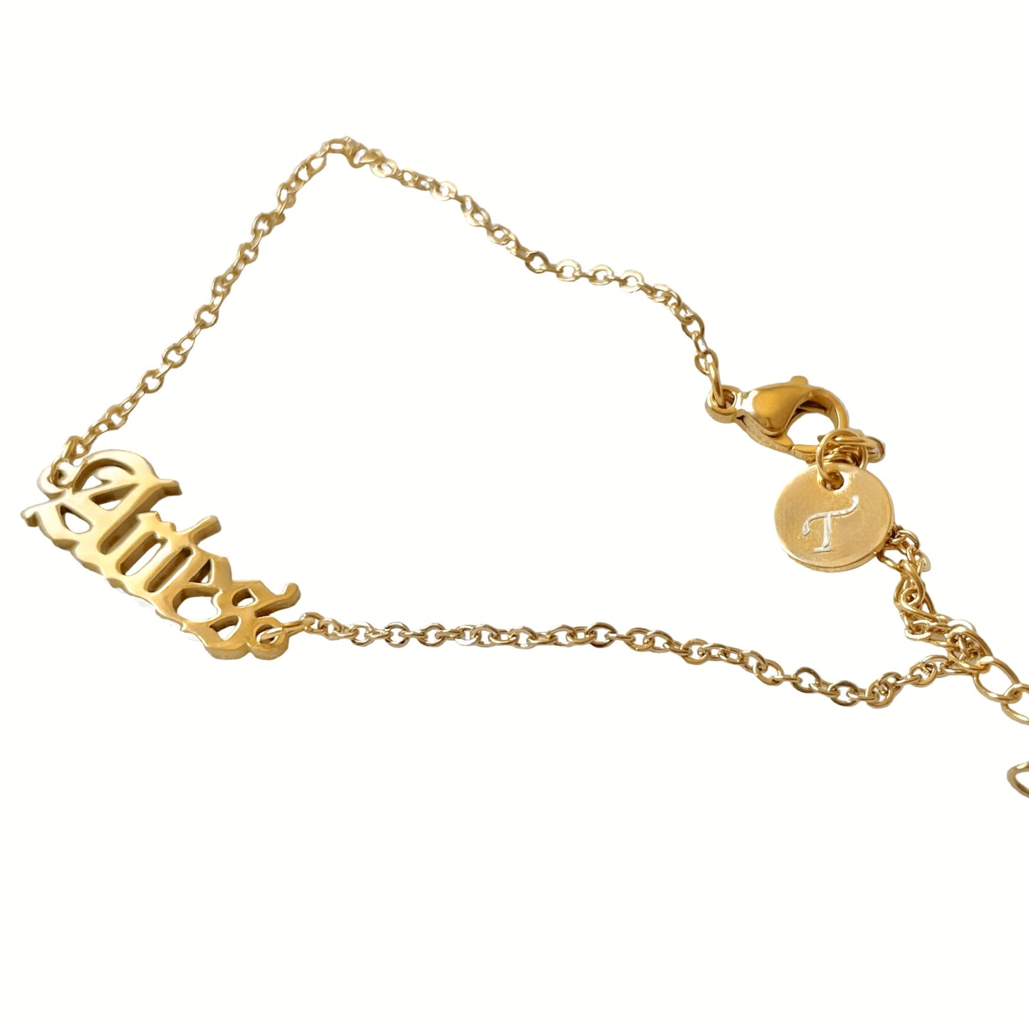 Gold ankle bracelet with 'Aries' and a circular  letter charm at the clasp on a white background