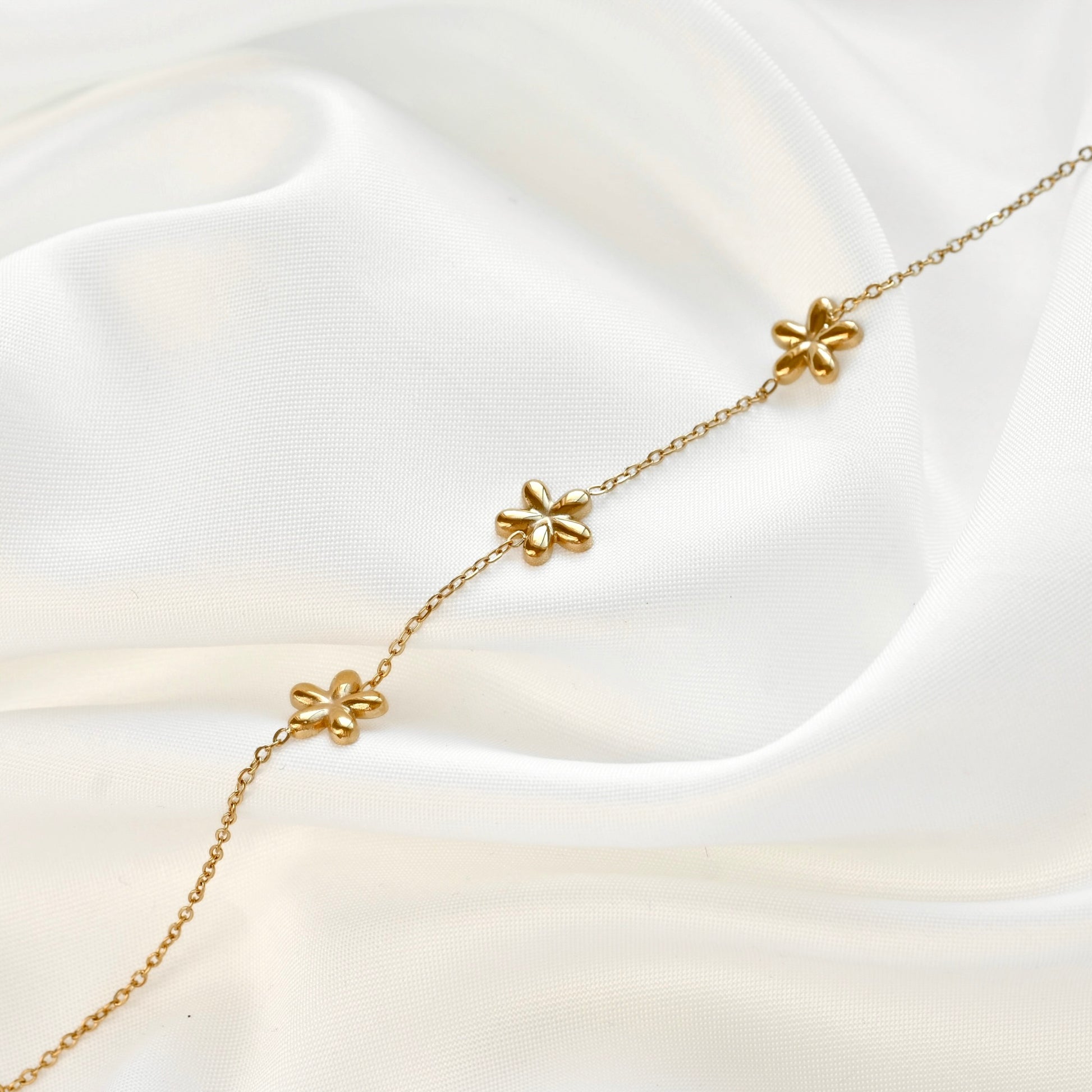 Gold bracelet with floral design on a white fabric background