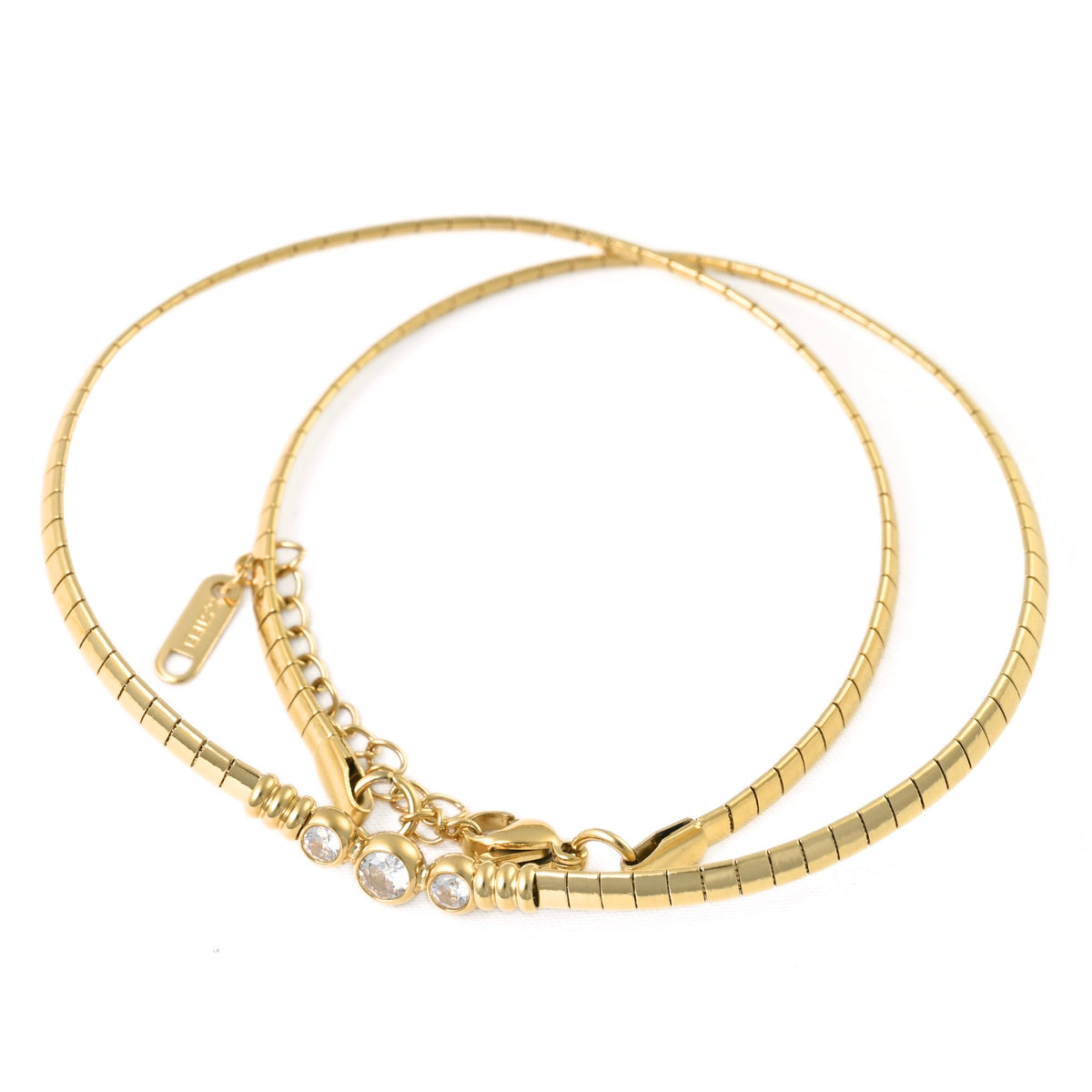 A gold-plated omega snake chain necklace with a lobster clasp, a small chain extension, and three clear rhinestone accents, displayed on a clean white background.