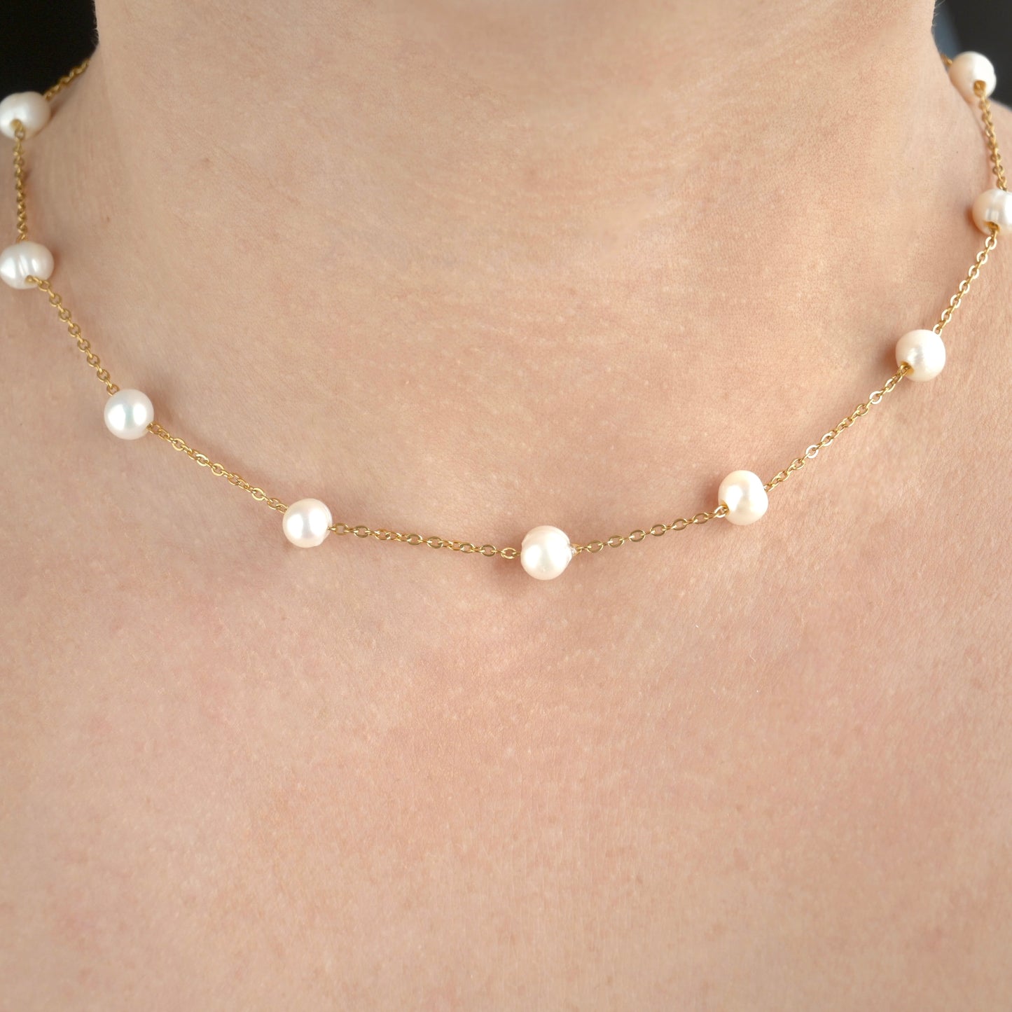 Front view of gold necklace with pearls on a person's neck