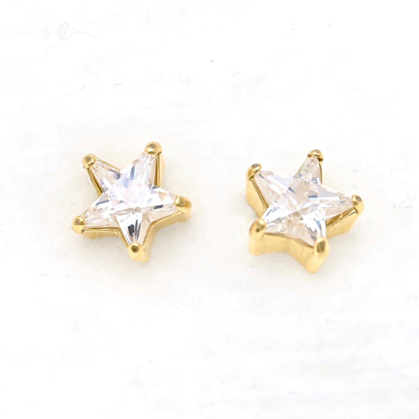 A pair of gold star-shaped stud earrings with star -shaped CZ, displayed on a clean white background.