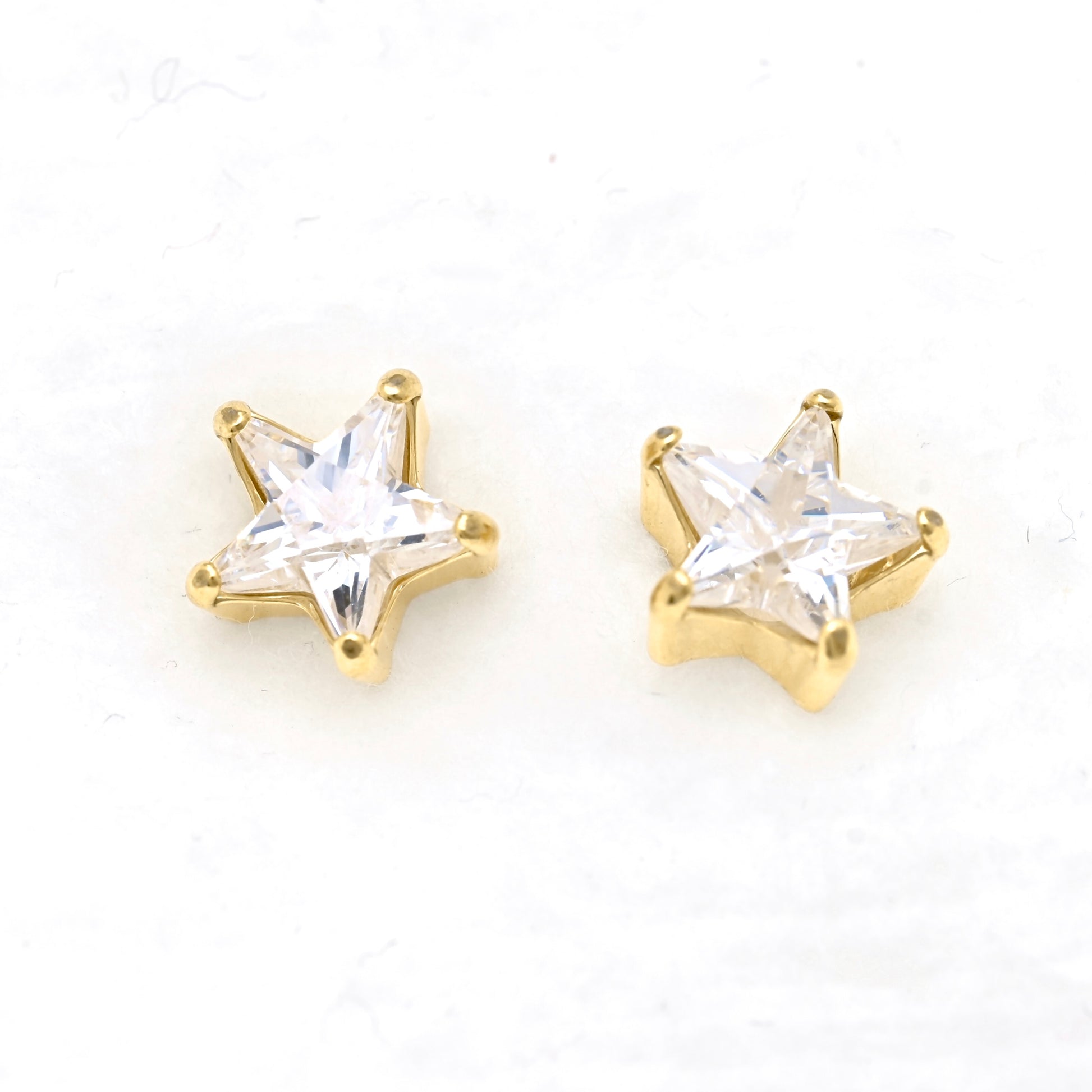 A pair of gold star-shaped stud earrings with star -shaped CZ, displayed on a clean white background.
