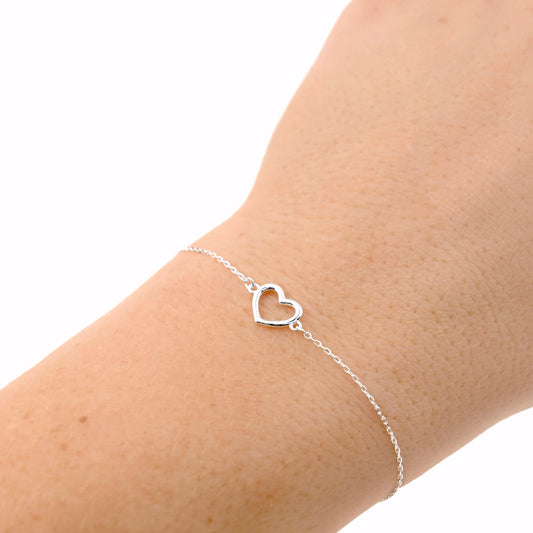 Silver heart outline bracelet on a wrist against a white background
