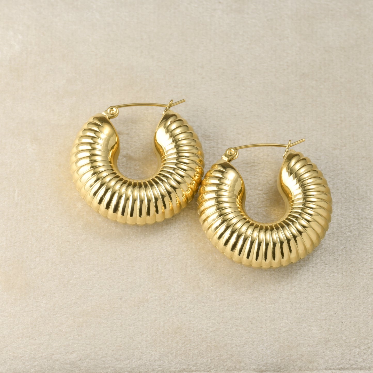 Textured Gold hoop earrings on a beige background