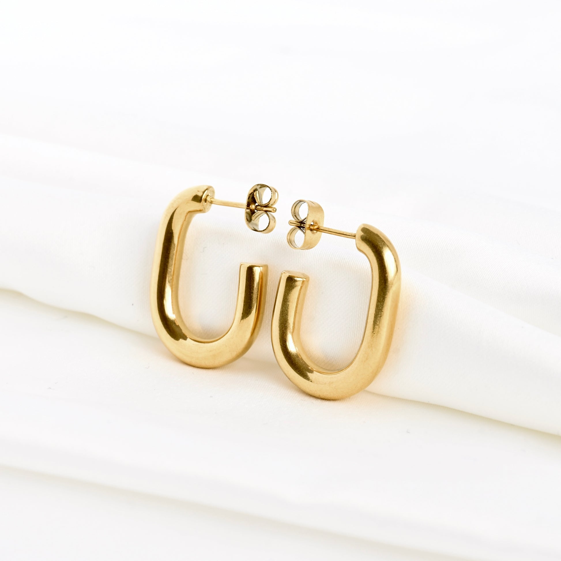 Angled front view of gold C hoop earrings with a U shape on a white background