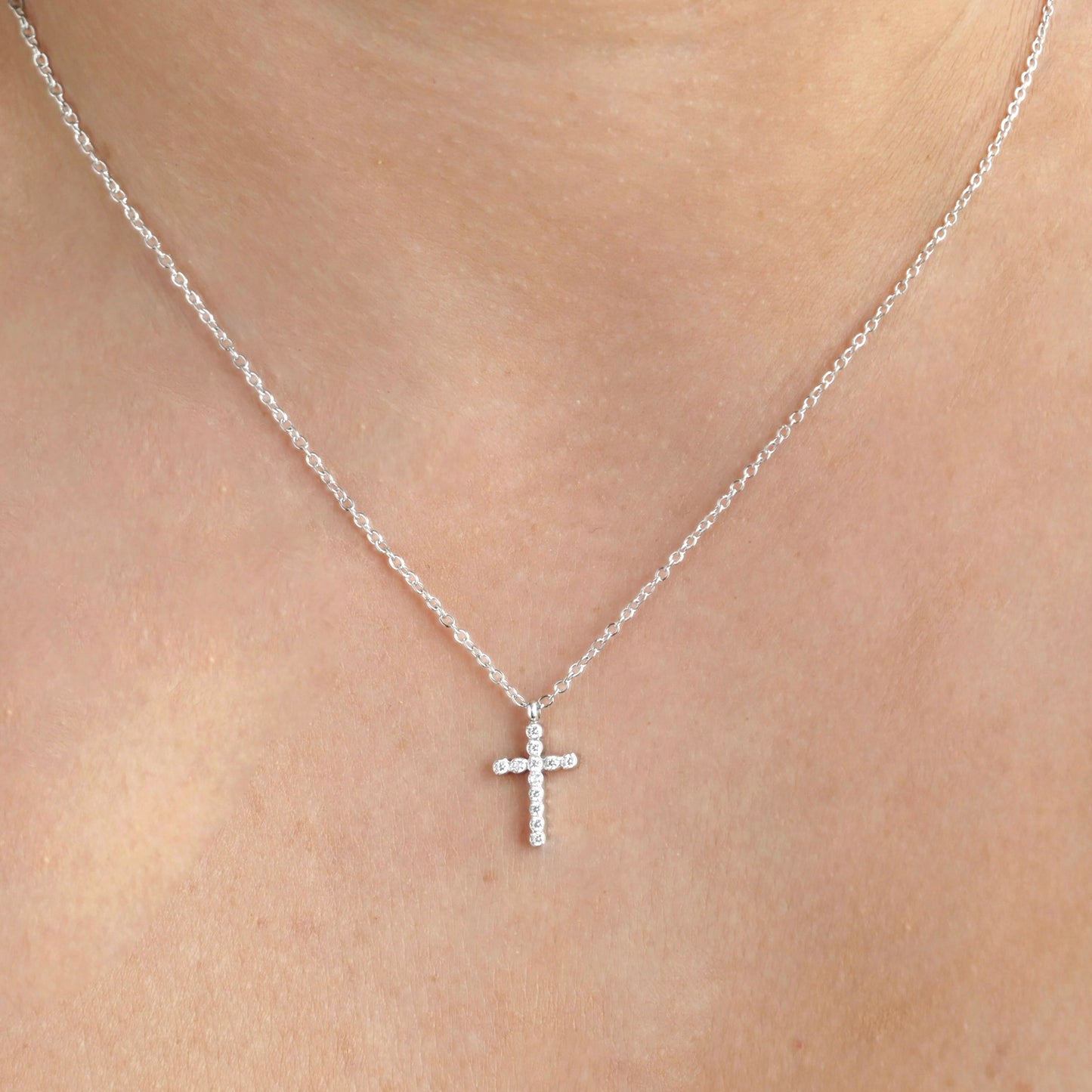 Front view of silver cross necklace on a person's neck