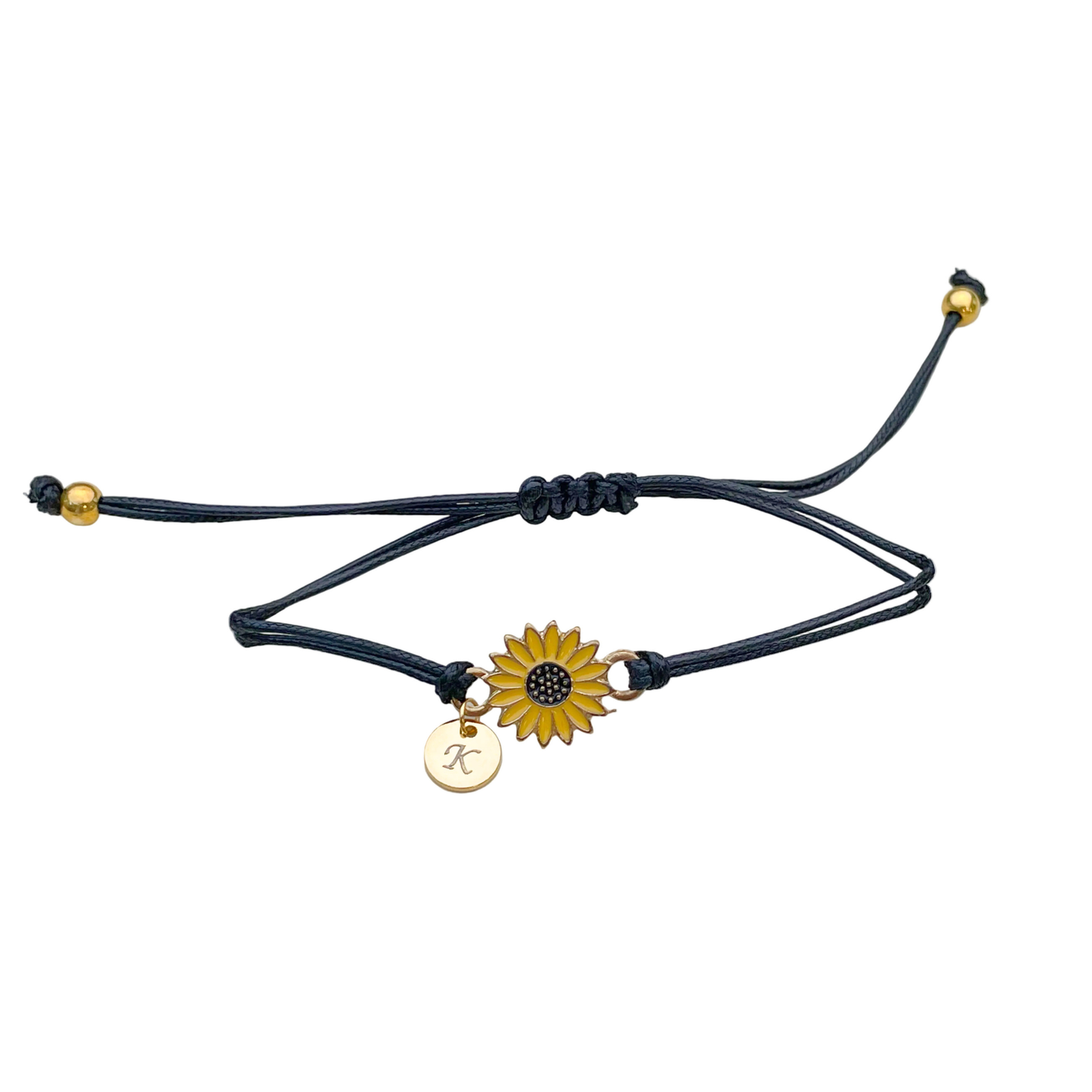 Black cord bracelet with a yellow sunflower charm, and initial disc and two gold beads on each end on a white background