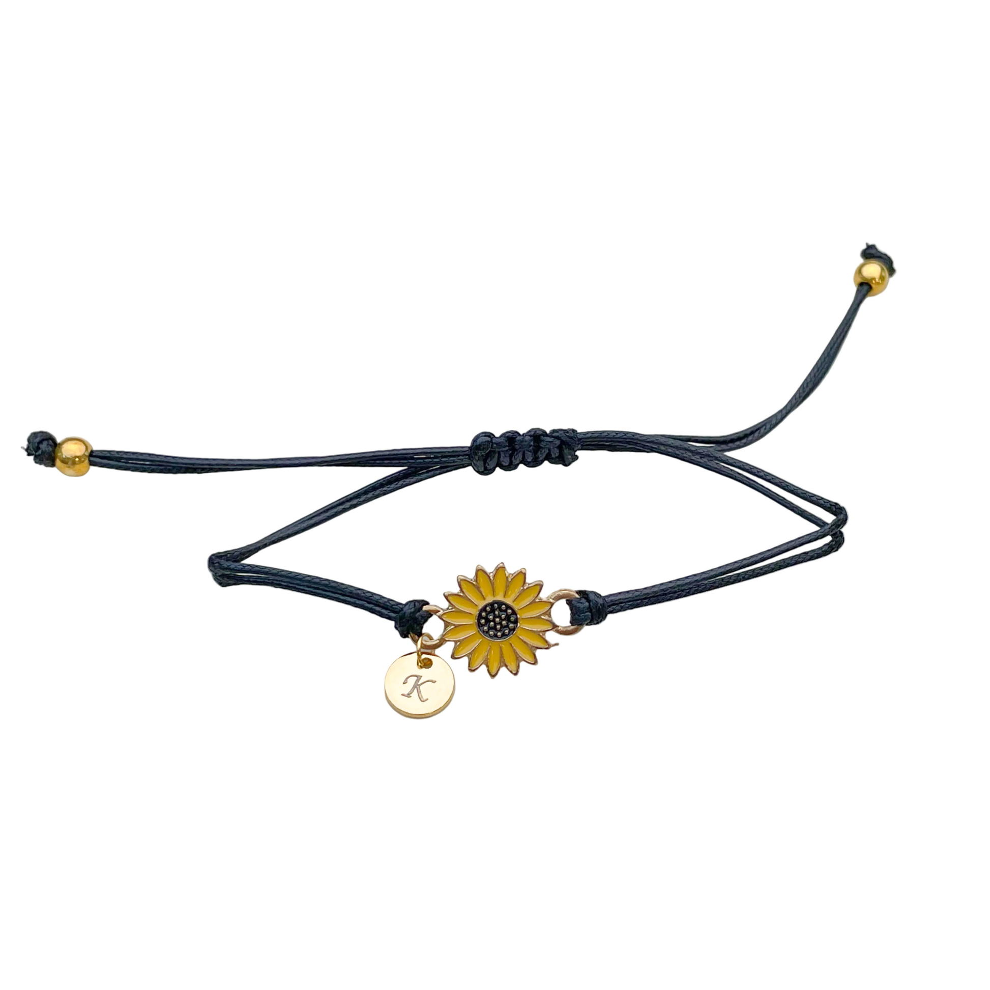 Black cord bracelet with a yellow sunflower charm, and initial disc and two gold beads on each end on a white background