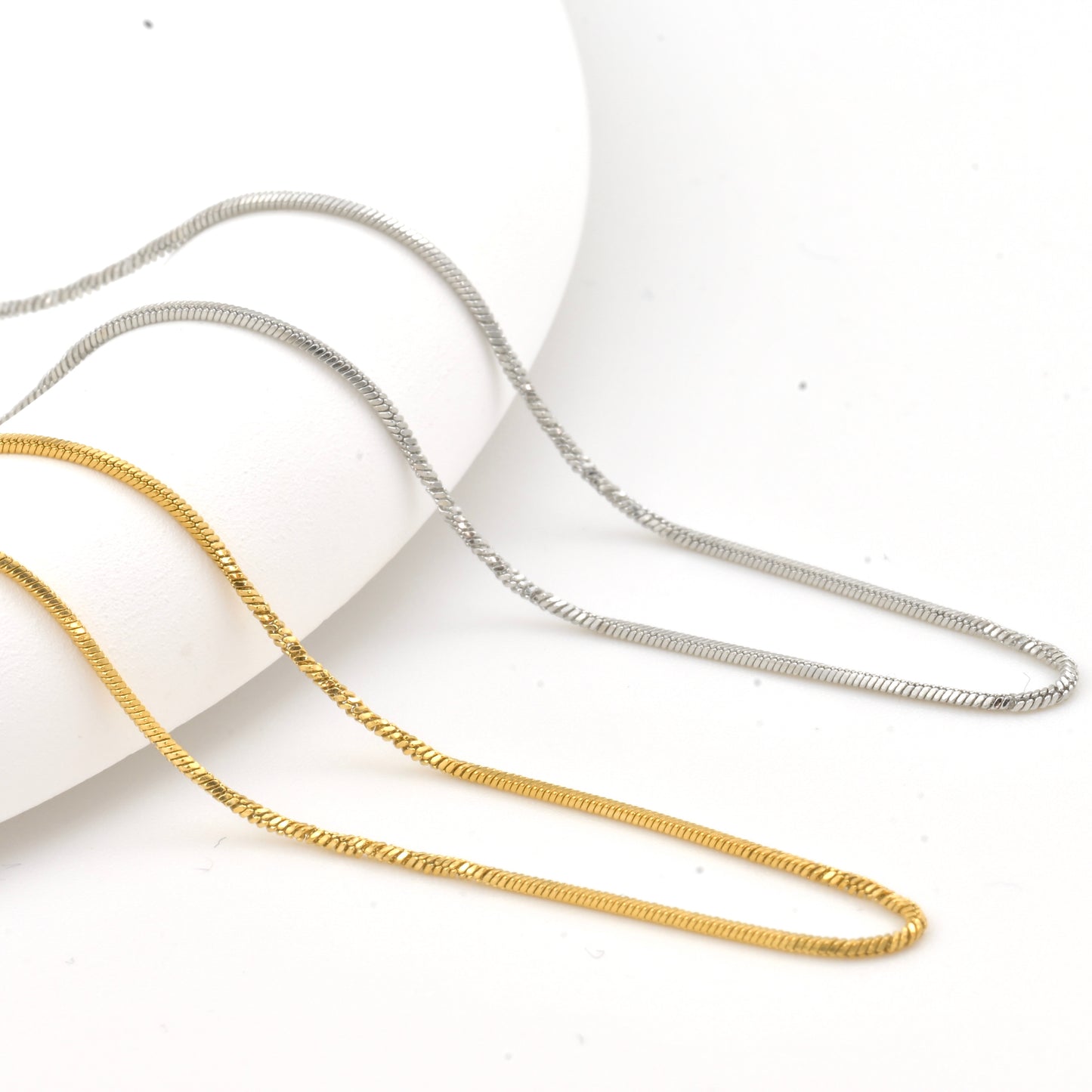 Twisted Gold and silver snake necklaces on a white background