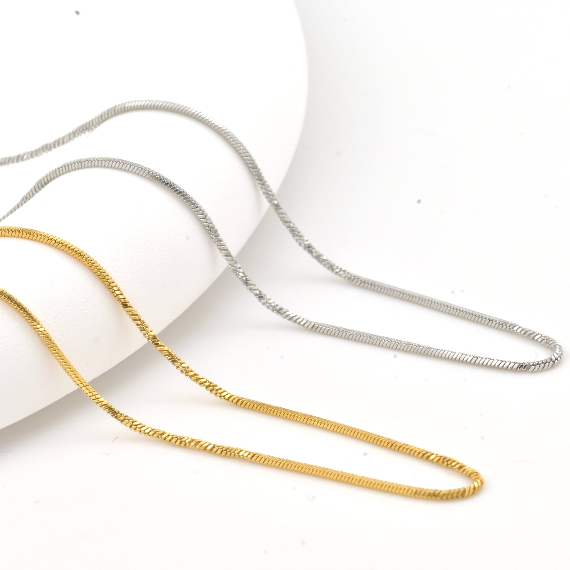 Twisted Gold and silver snake necklaces on a white background