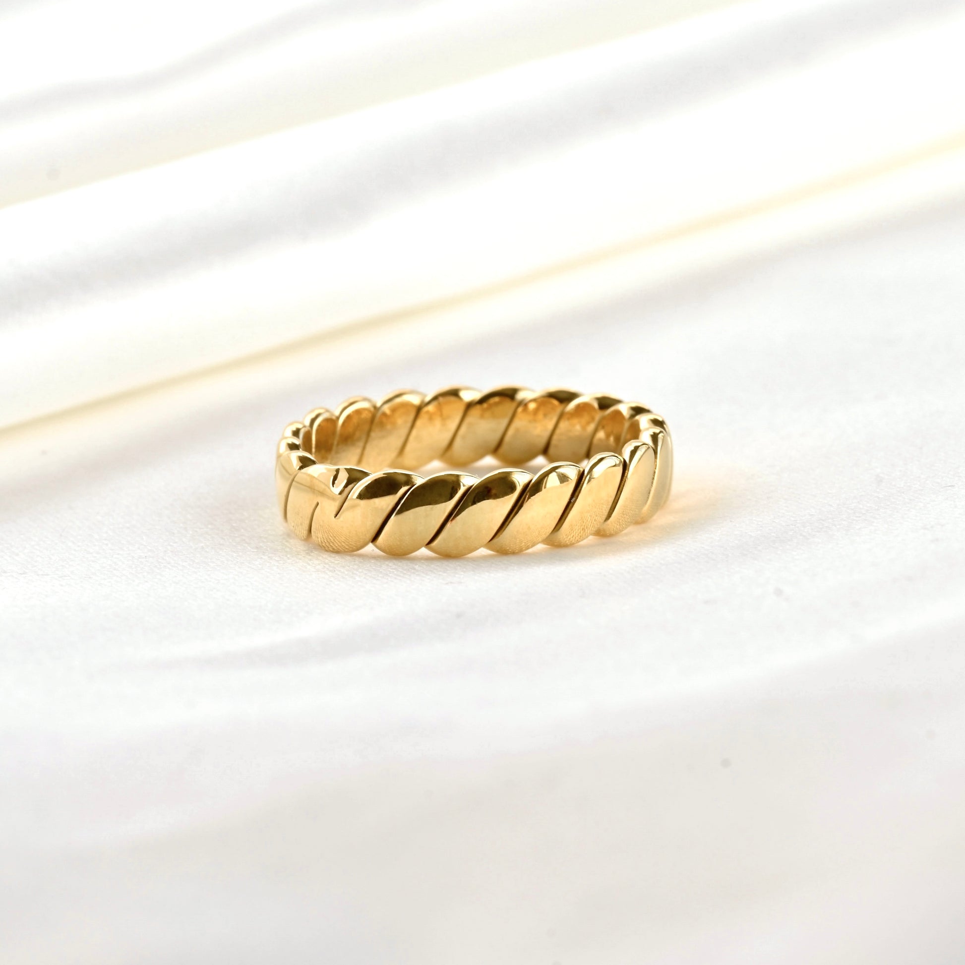 Close-up view of braided gold ring on a white background