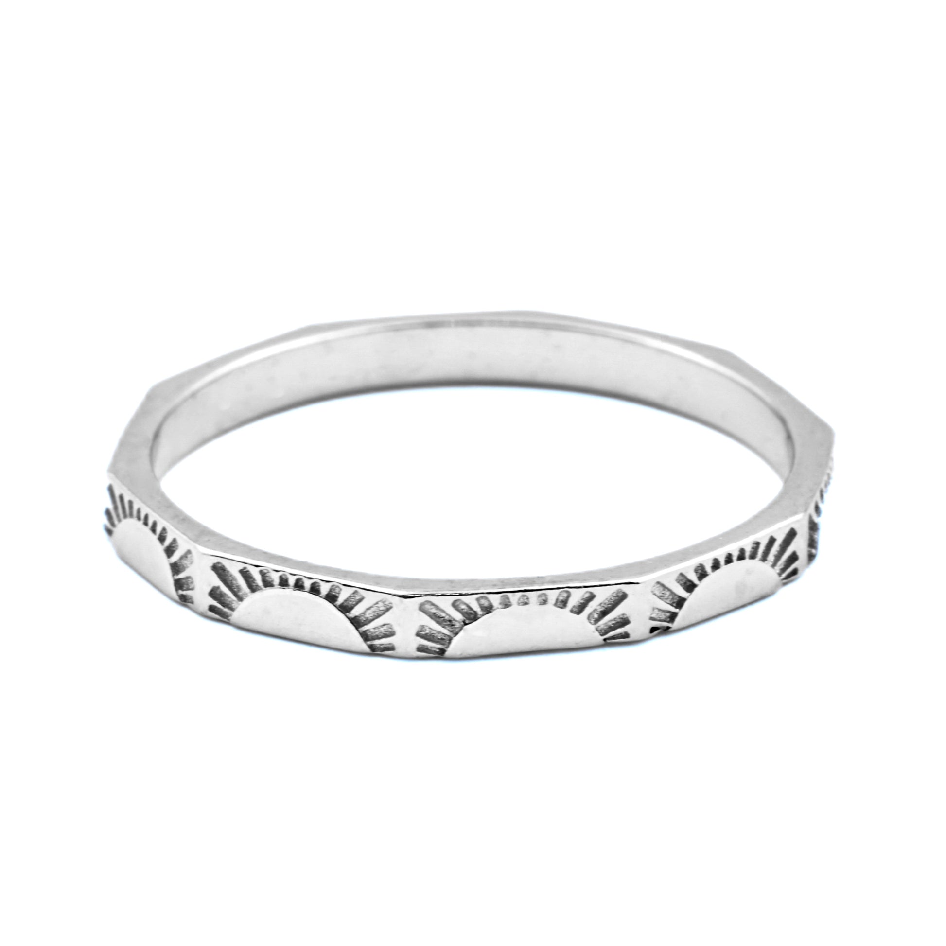 Angular silver sunburst  ring with a textured design on a white background