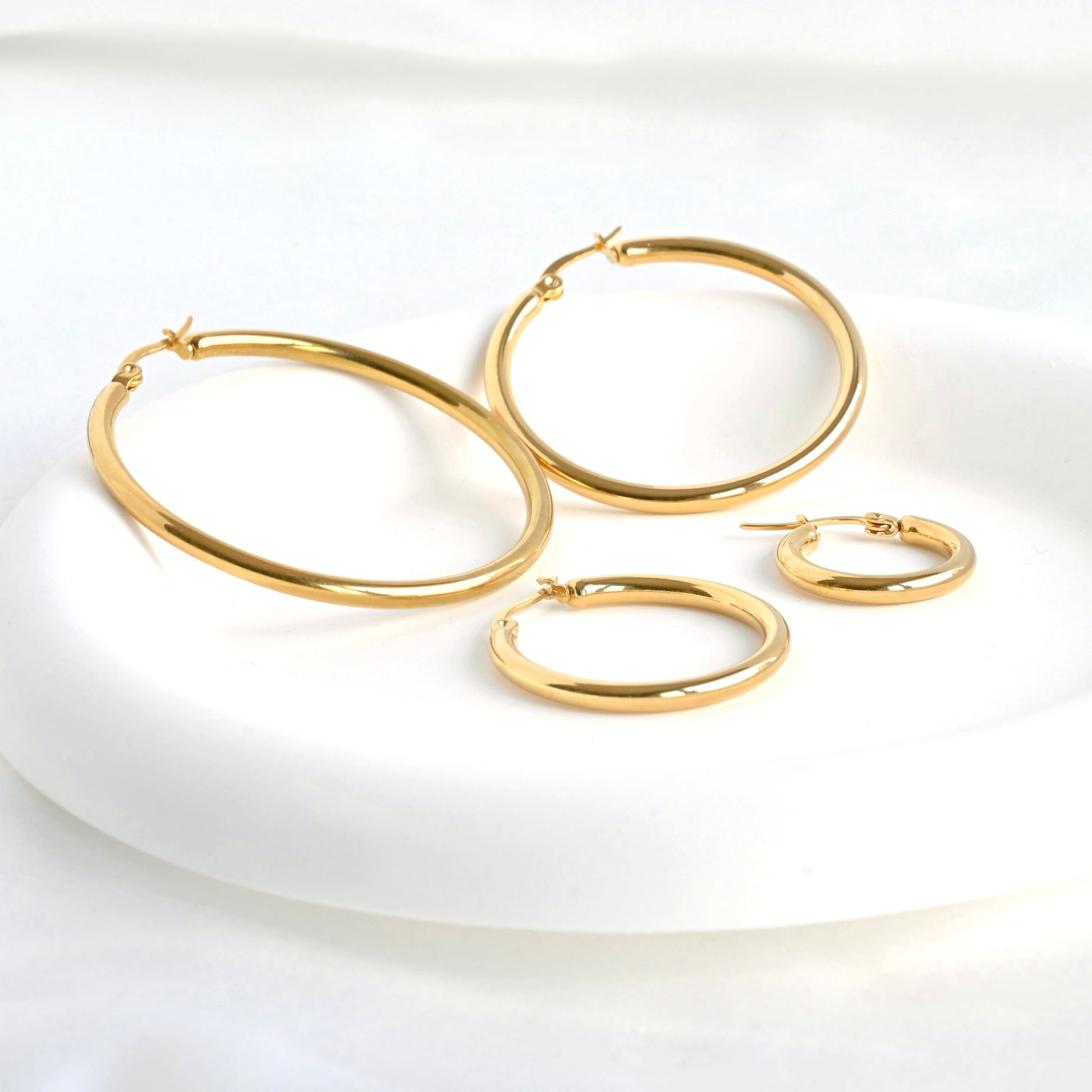 Set of gold hoop earrings on a white plate