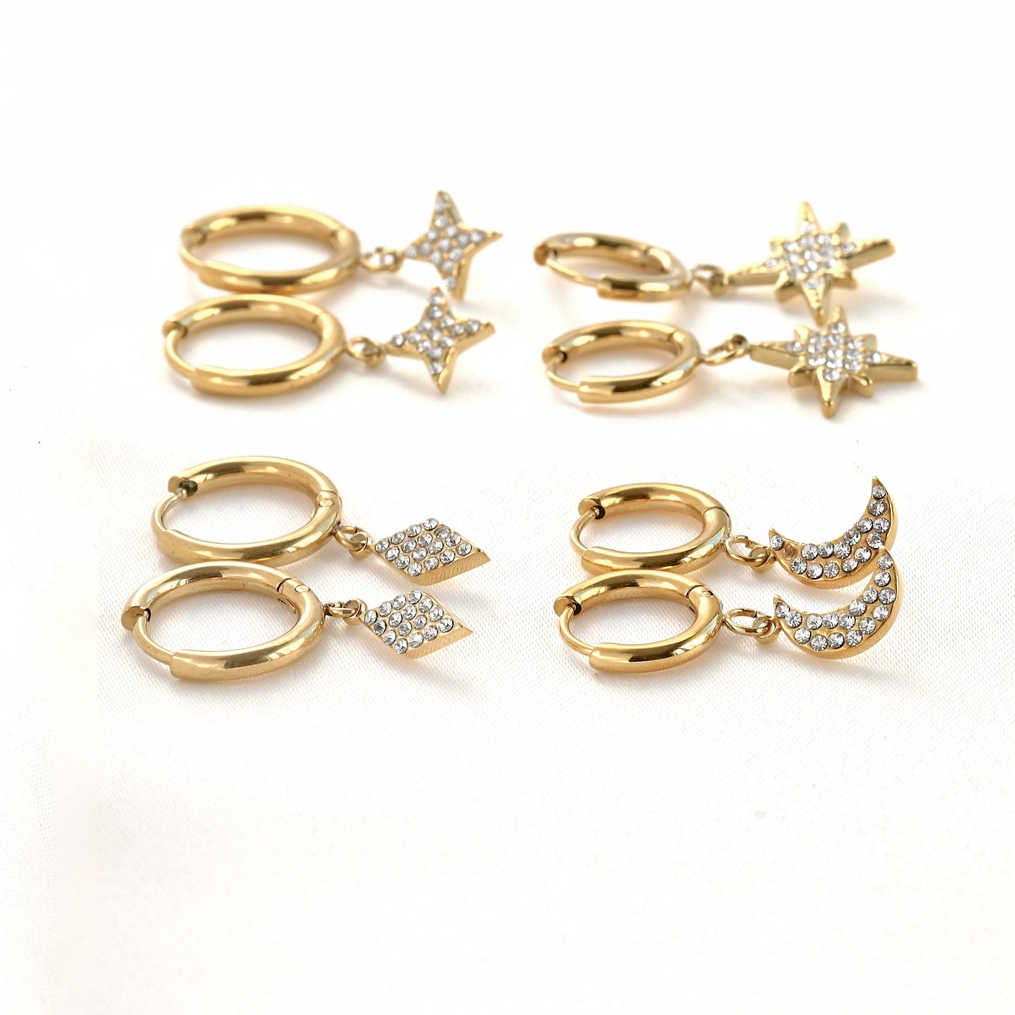 Side view of gold earrings set with star and moon charms on a white background