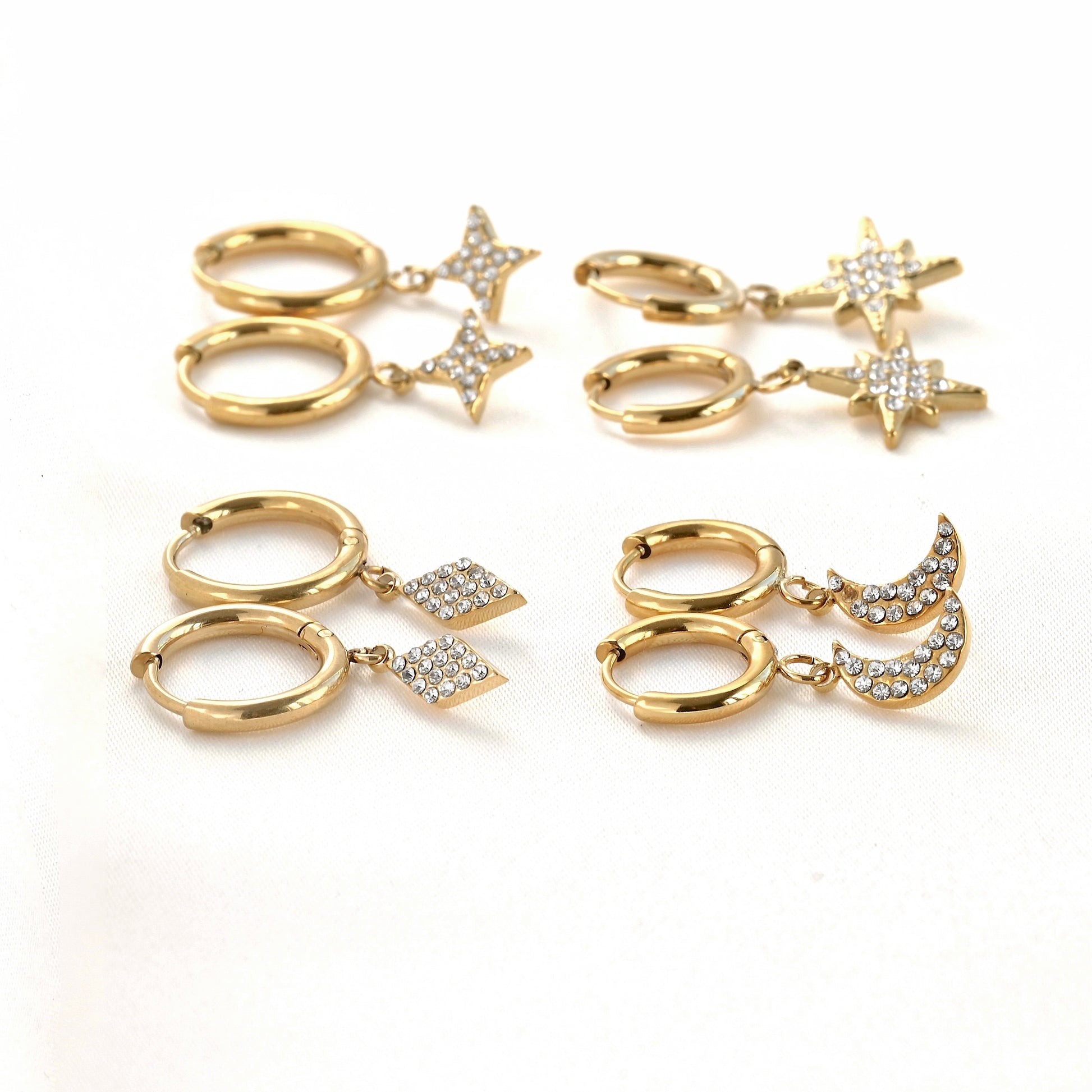 Side view of gold earrings set with star and moon charms on a white background