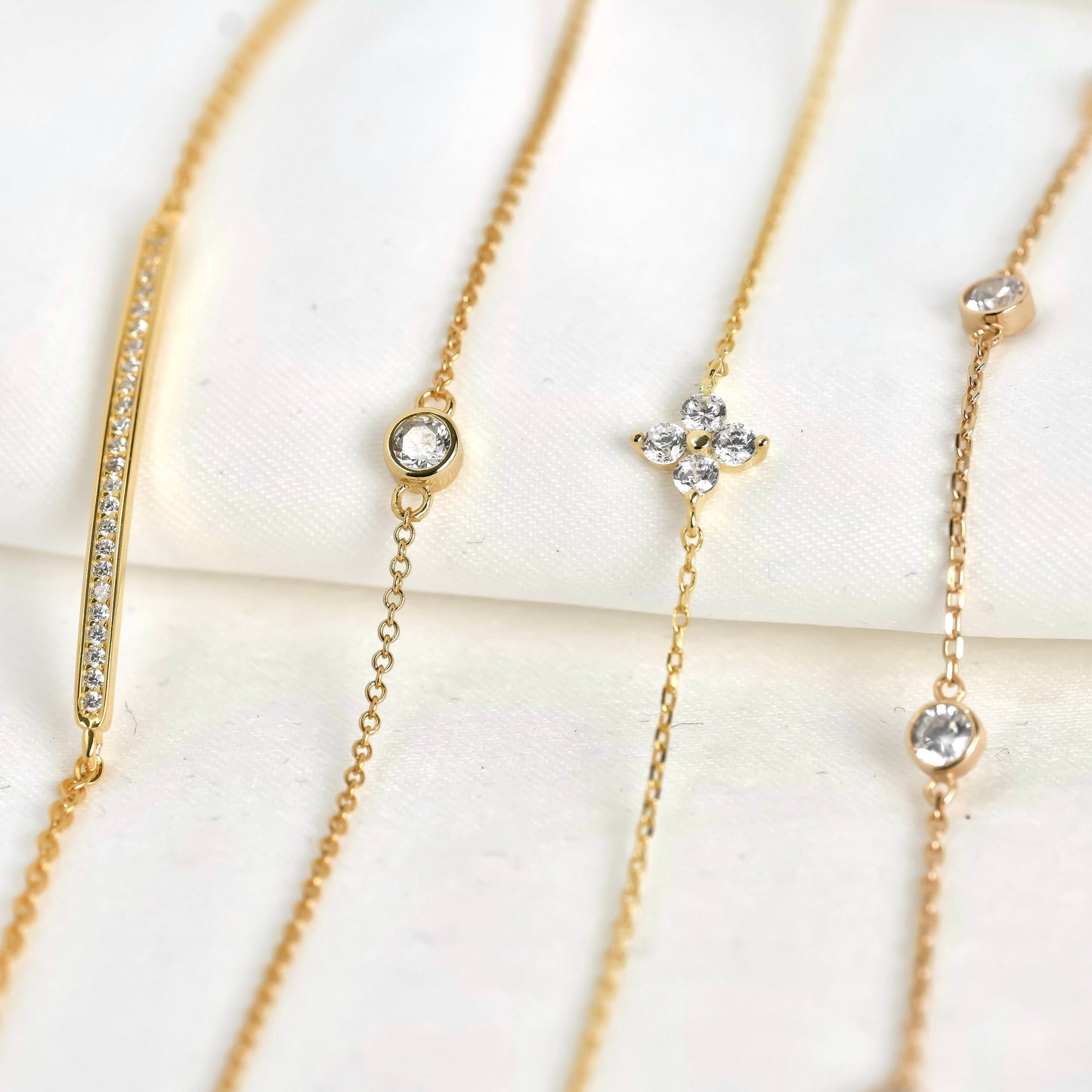 Front view of gold bracelets with flower and bar details on a white background