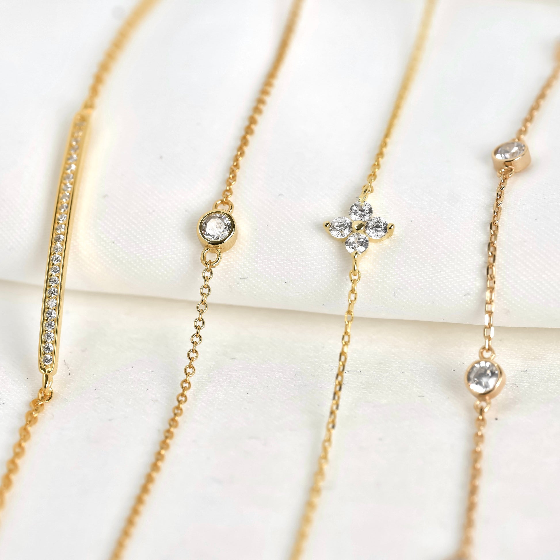 Front view of gold bracelets with flower and bar details on a white background