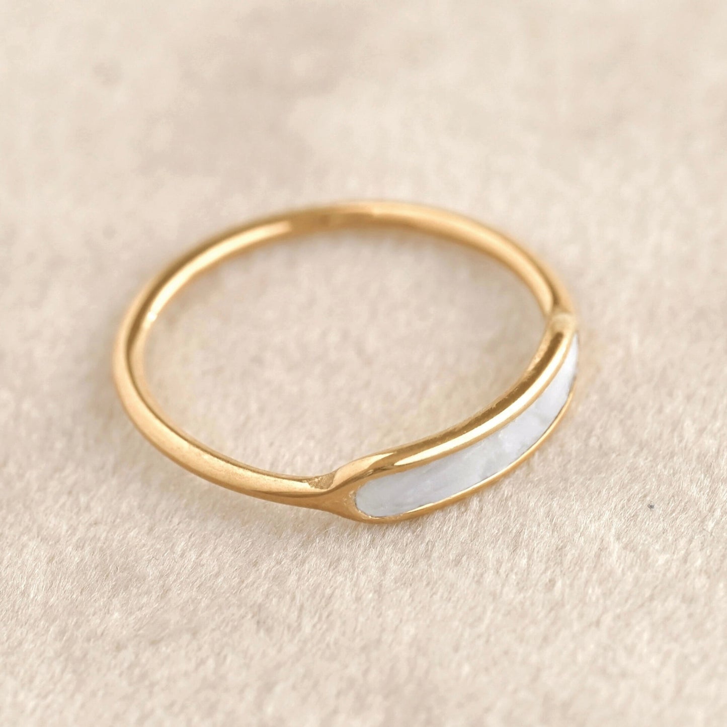 Waterproof gold ring with a shell inlay on a beige background