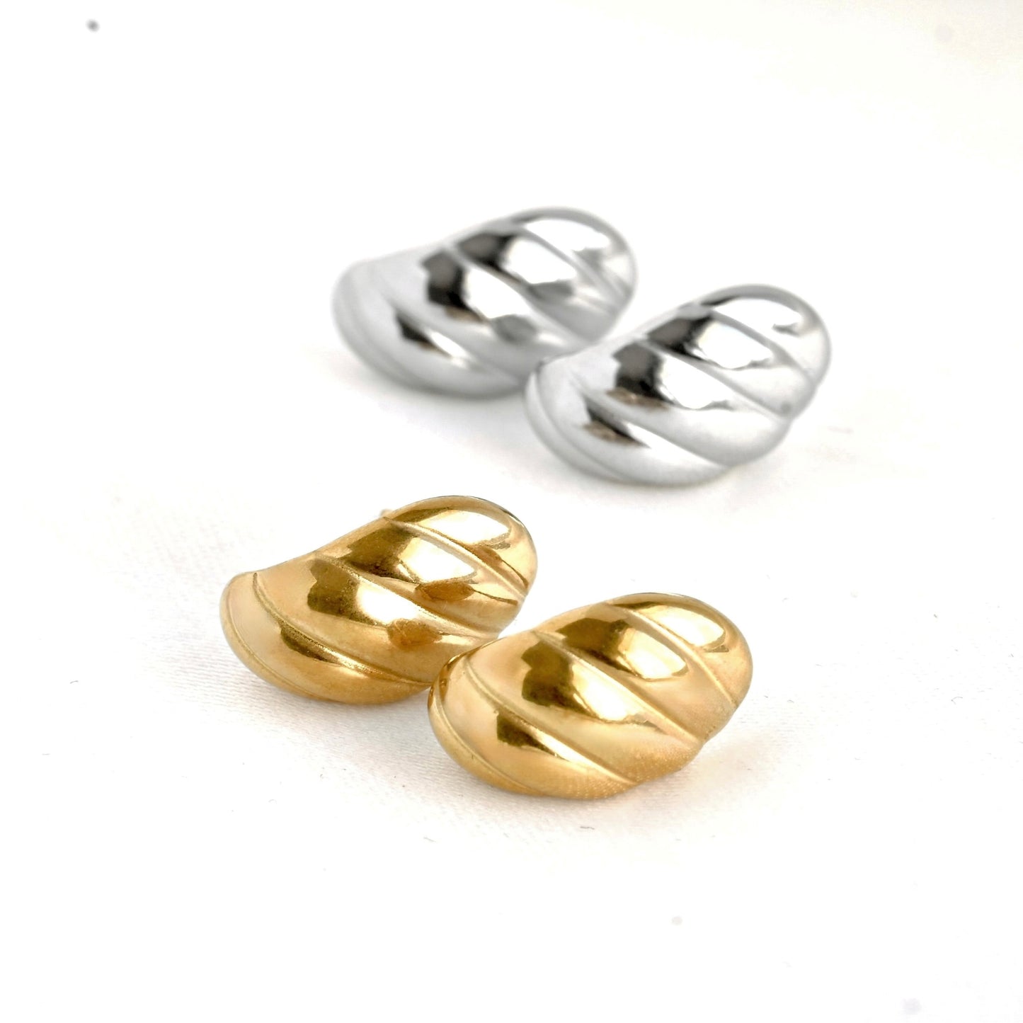 Pair of small gold and silver huggie hoop earrings on a white background