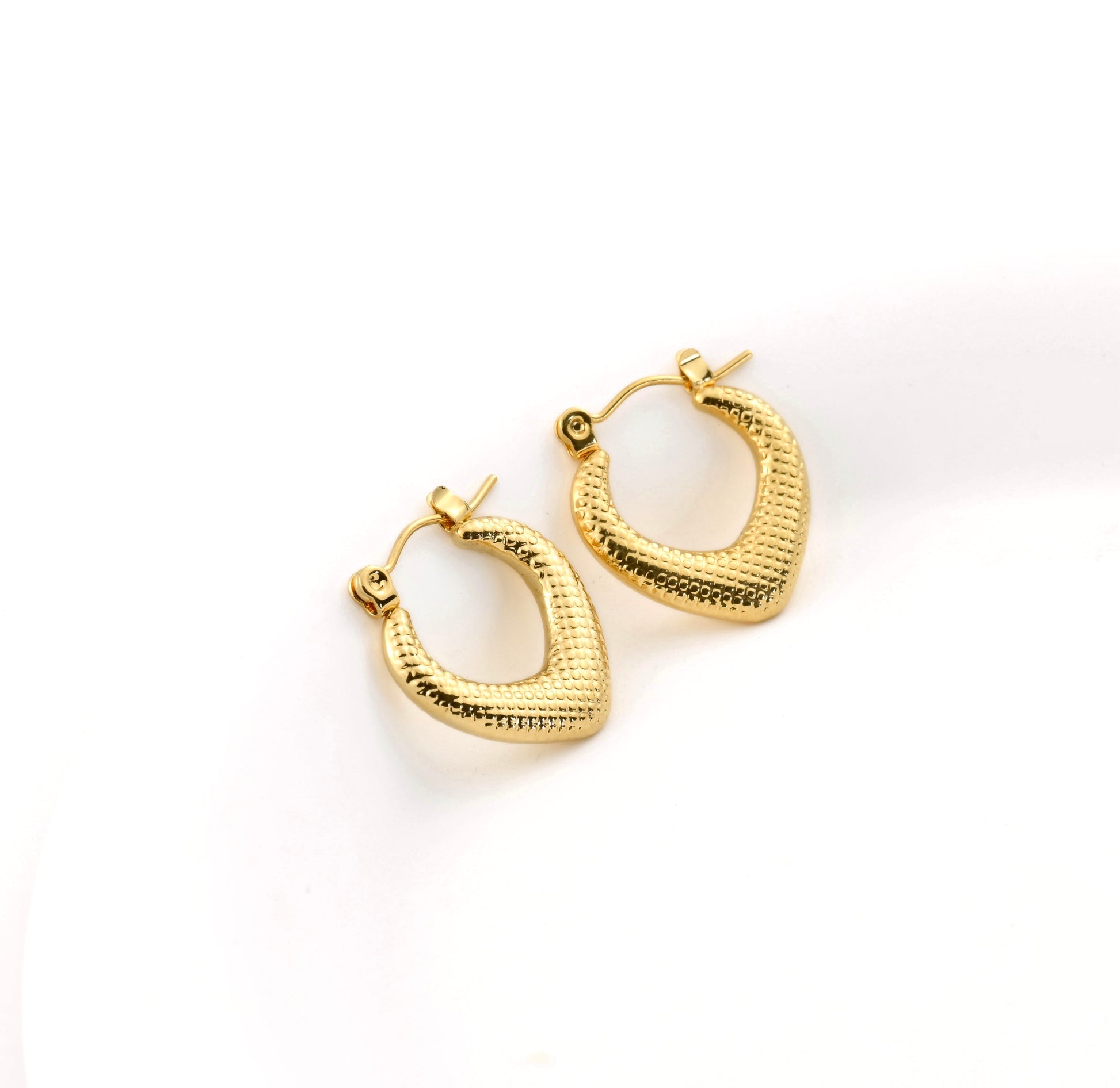 Dotted geometric gold hoop earrings on a white background