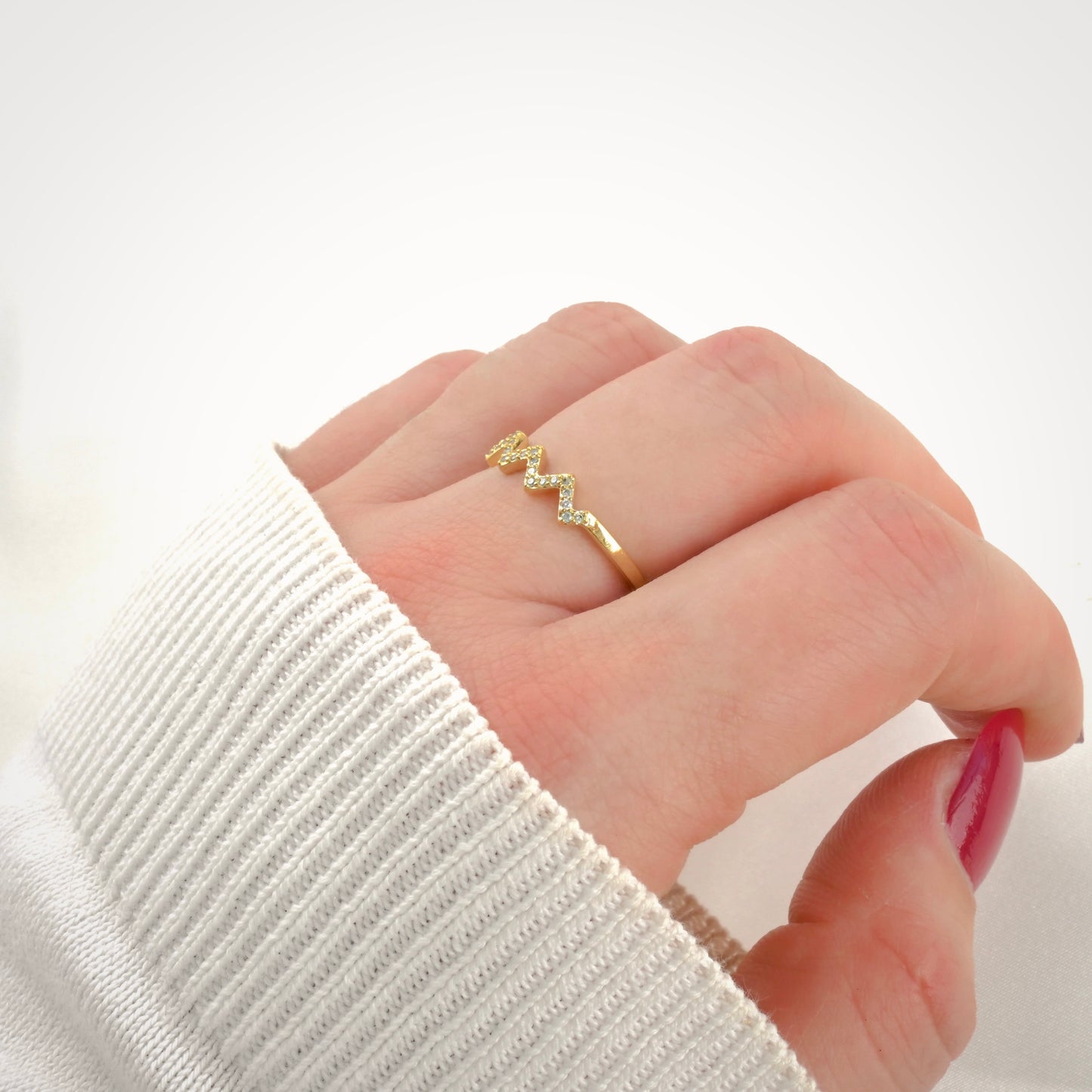 Side view of hand wearing a gold ring with a white background
