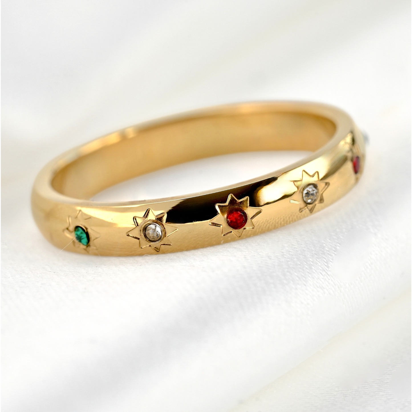 Gold ring with star-set CZ stones in green, white and red on a white background