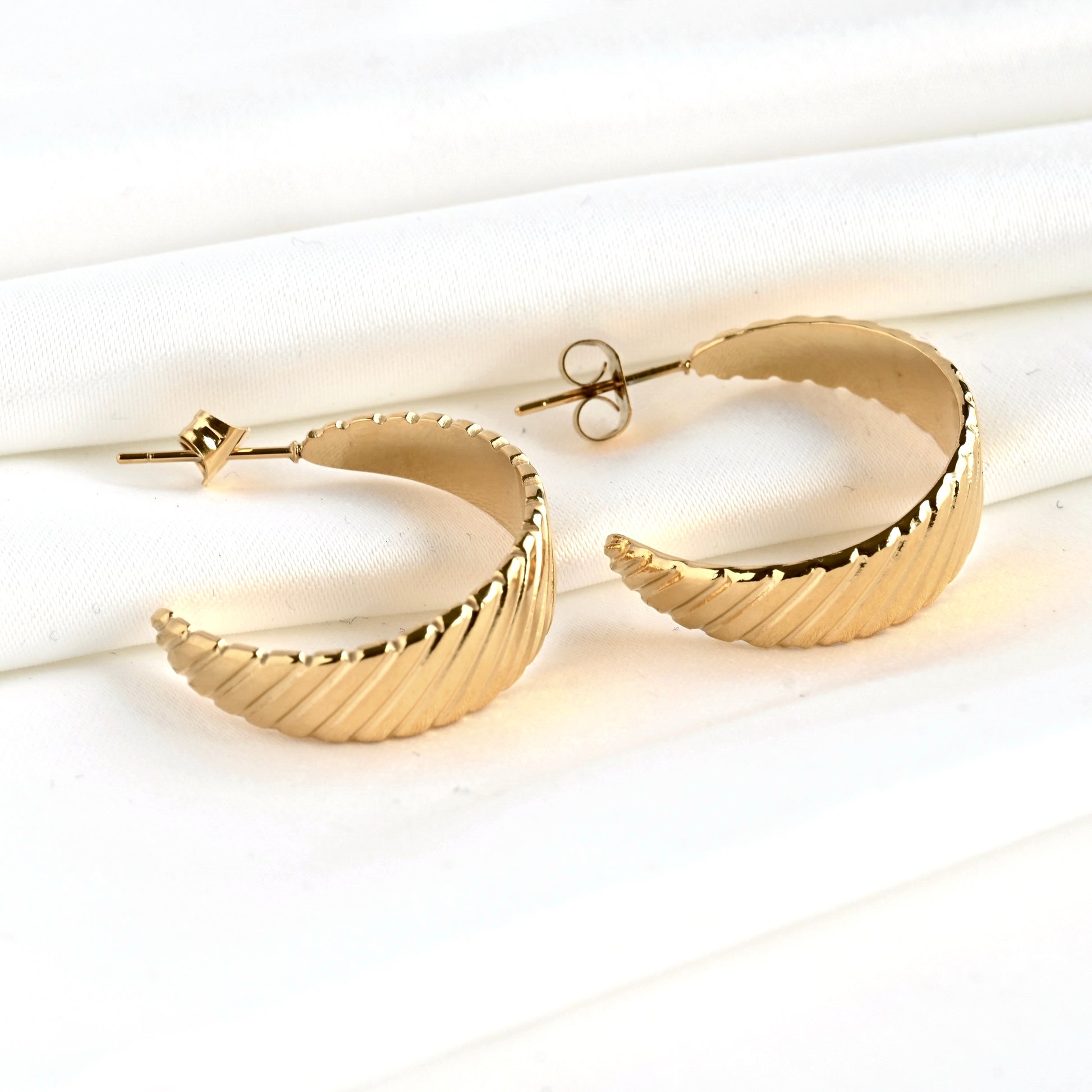 Gold crescent C hoop earrings on a white surface