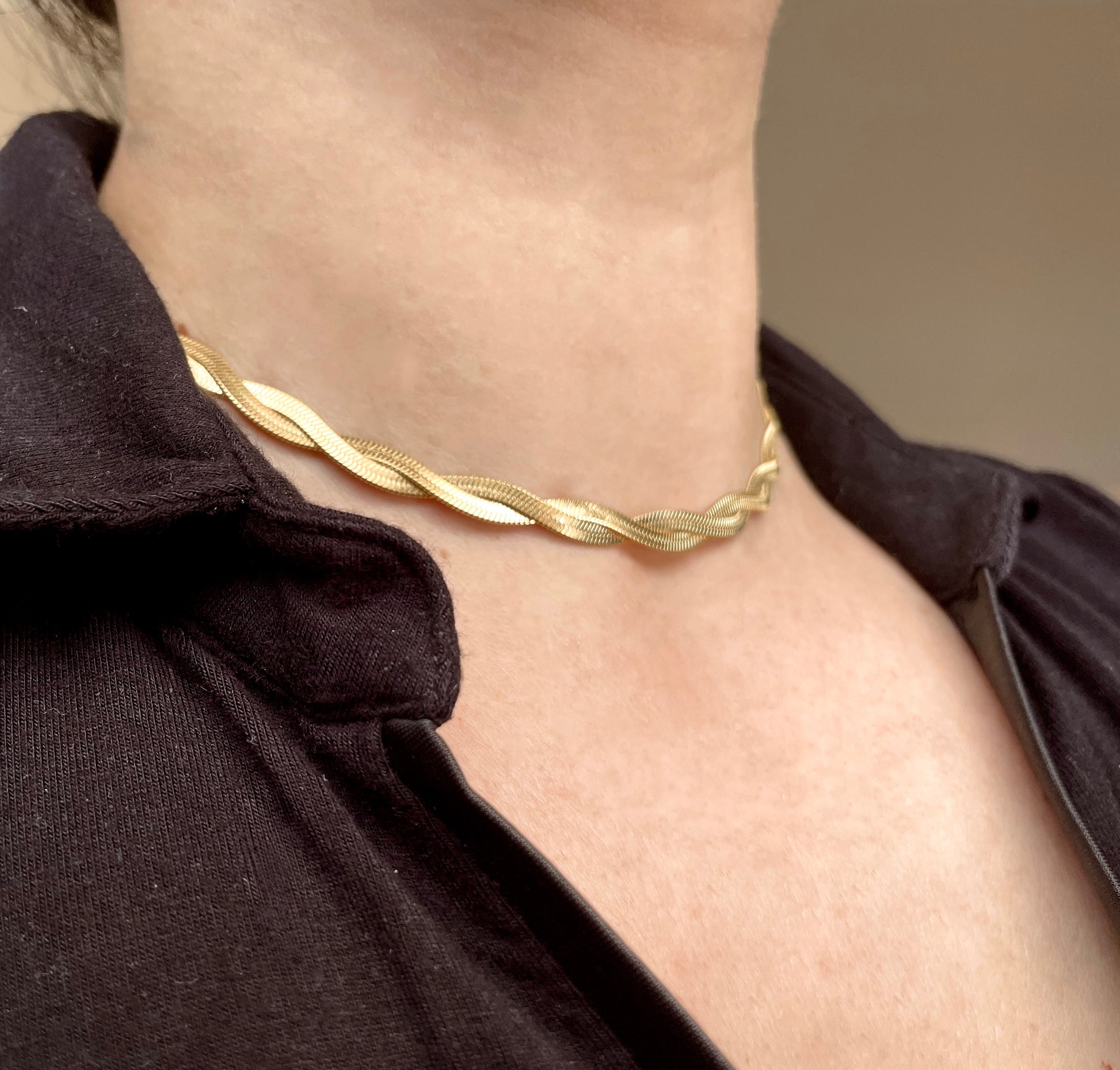 Gold twisted herringbone choker necklace on a person wearing a black shirt