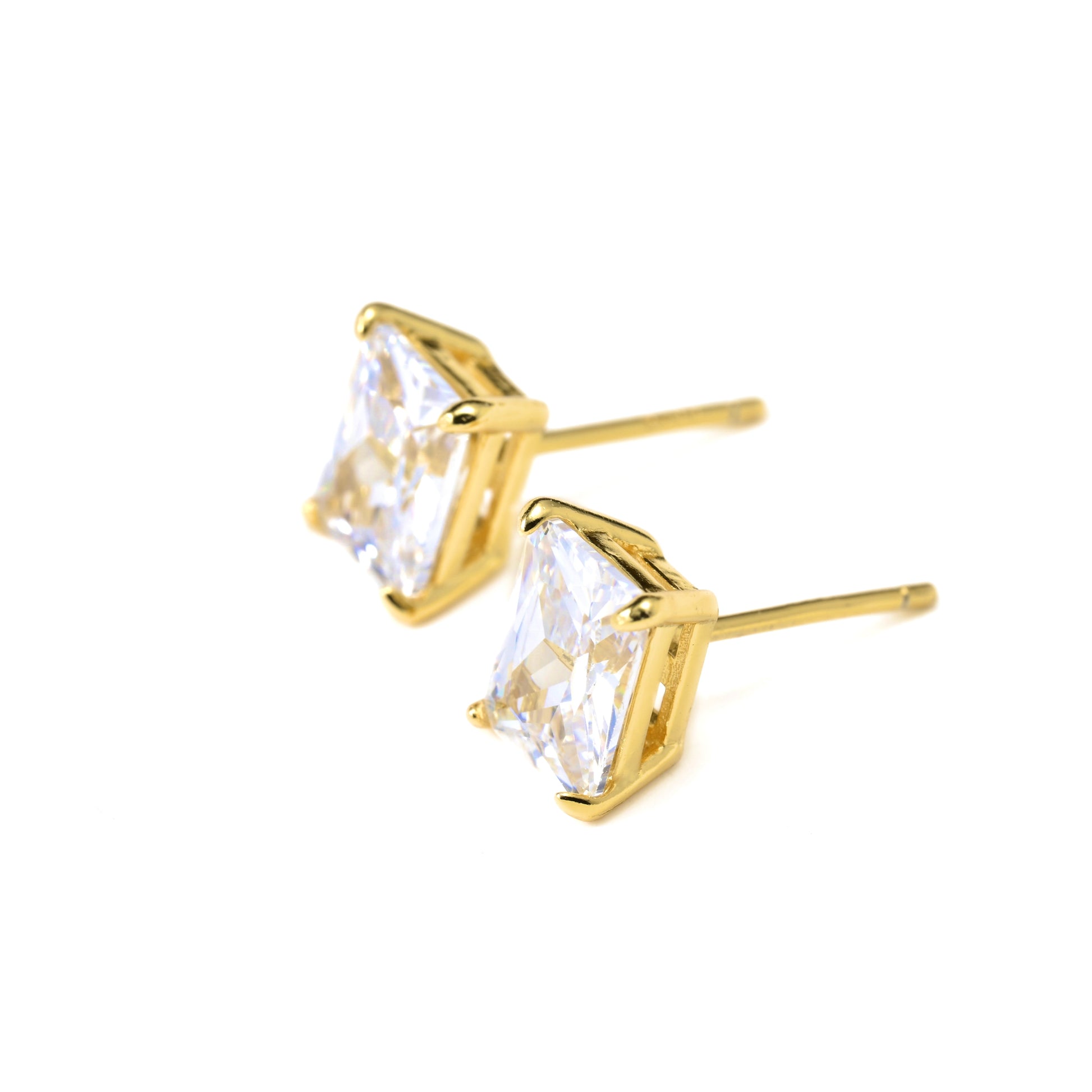 Gold solitaire stud earrings with clear gemstones on a white background