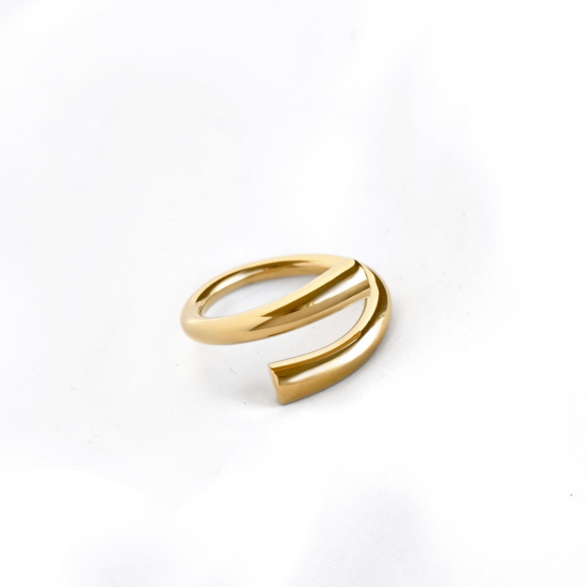 A polished gold open wrap ring with a modern, curved design, photographed on a clean white background.