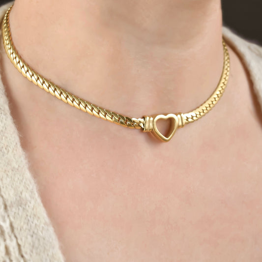 Gold chain necklace with a heart charm worn by a person