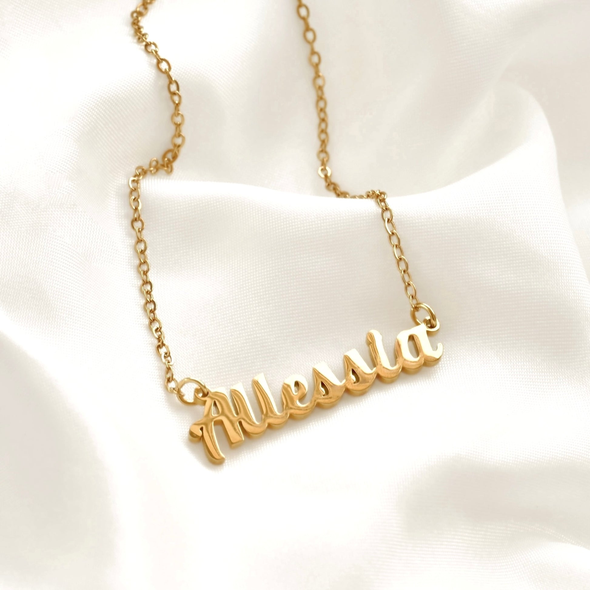 Gold name bracelet on a white fabric background